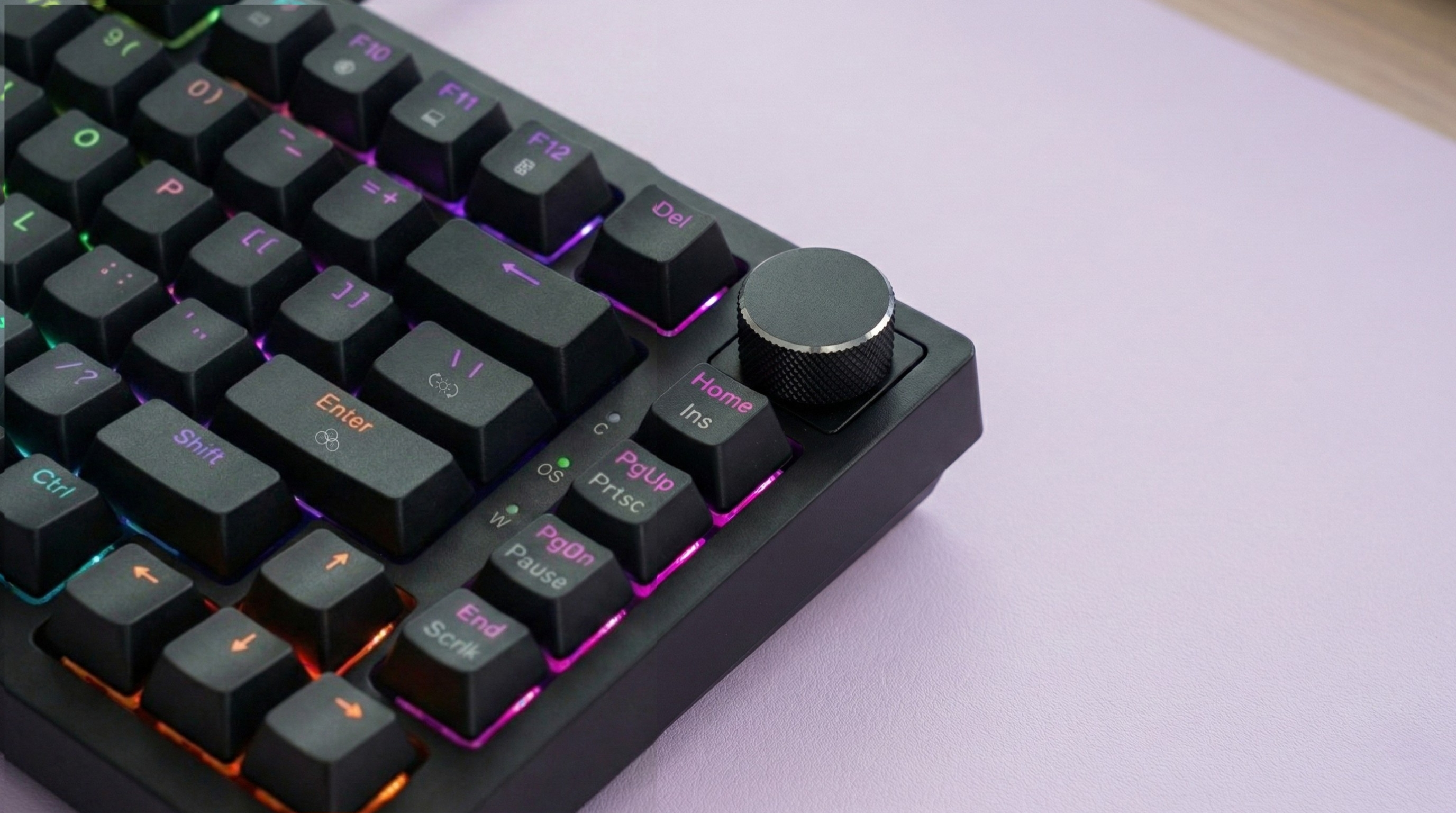 Czarna klawiatura z podświetleniem RGB i pokrętłem na fioletowej macie.