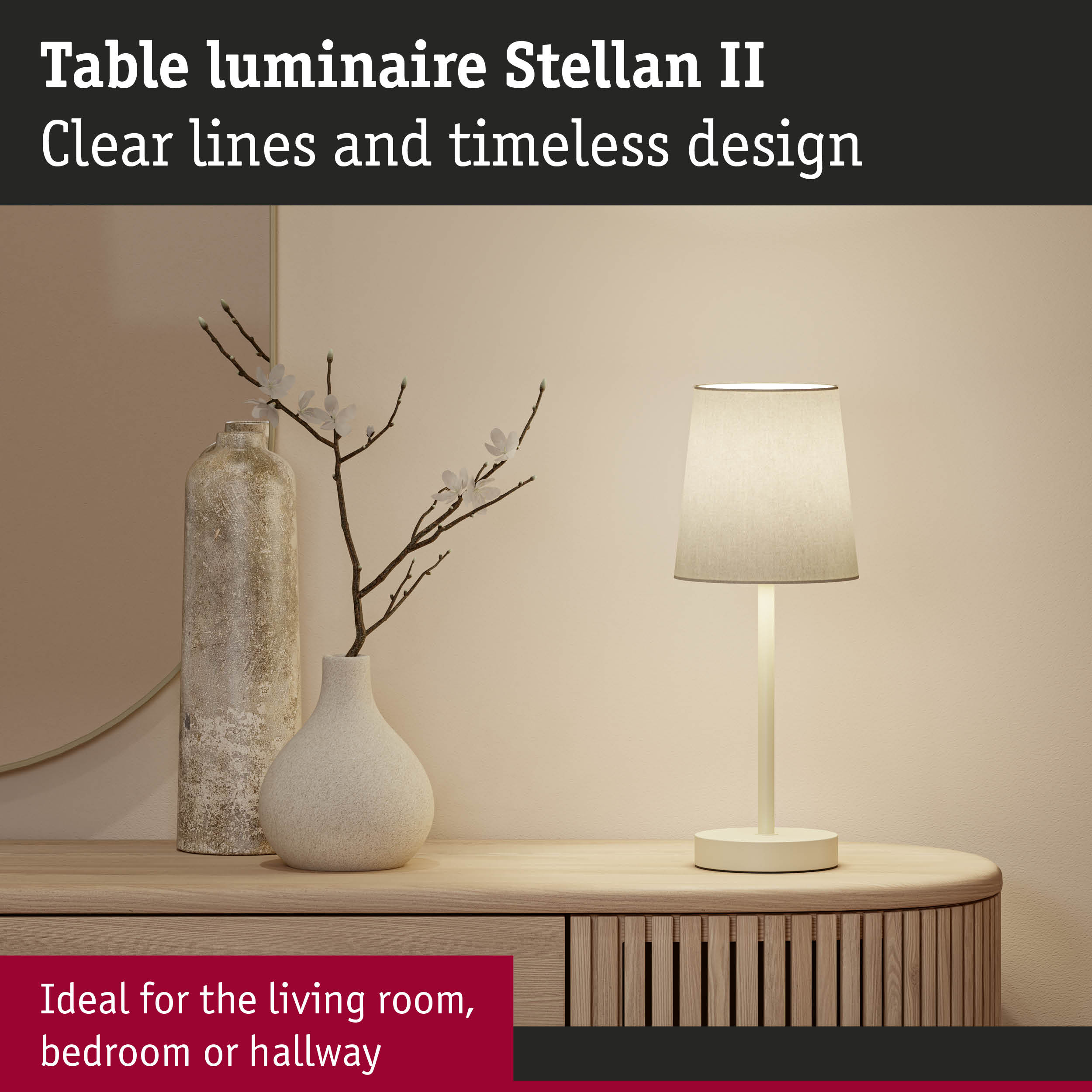 Biała lampa stołowa stoi obok wazonu z gałęziami na drewnianej komodzie.