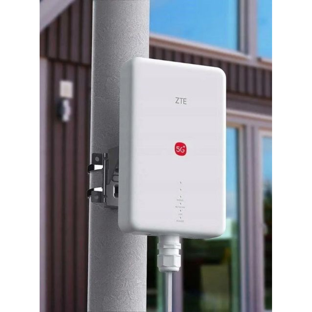 Białe urządzenie ZTE 5G jest przymocowane do okrągłego słupa. Tło to dom.