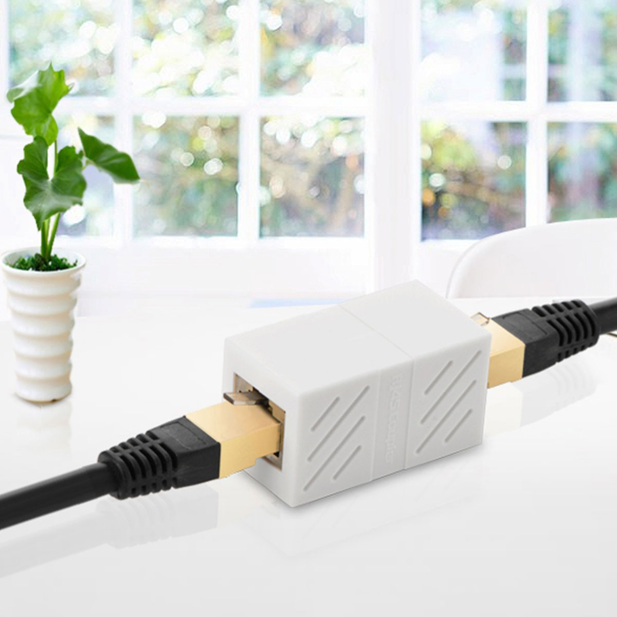 Białe złącze kablowe łączy dwa czarne kable ze złotymi wtyczkami.