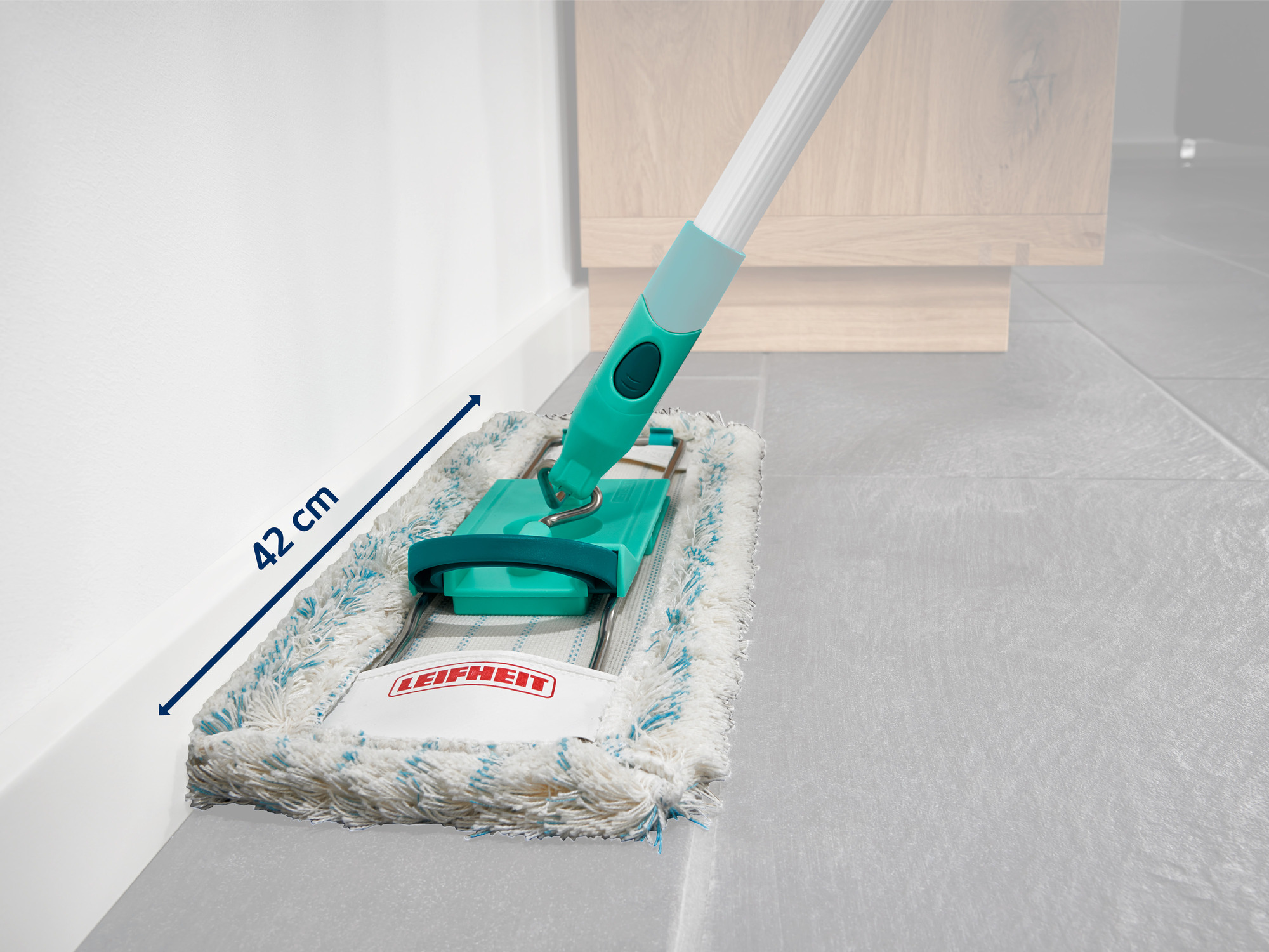 Ein Leifheit-Bodenwischer mit blau-weißer Bespannung steht neben einer weißen Wand.