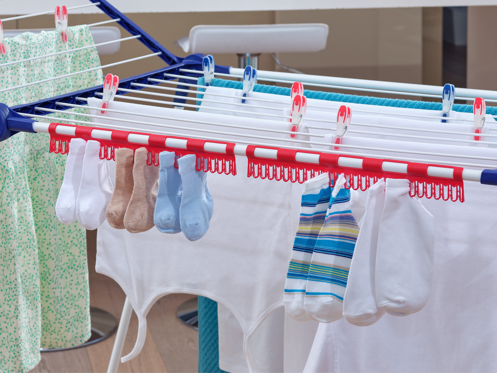 Wäscheständer mit bunten Socken und Kleidung, die zum Trocknen aufgehängt ist.