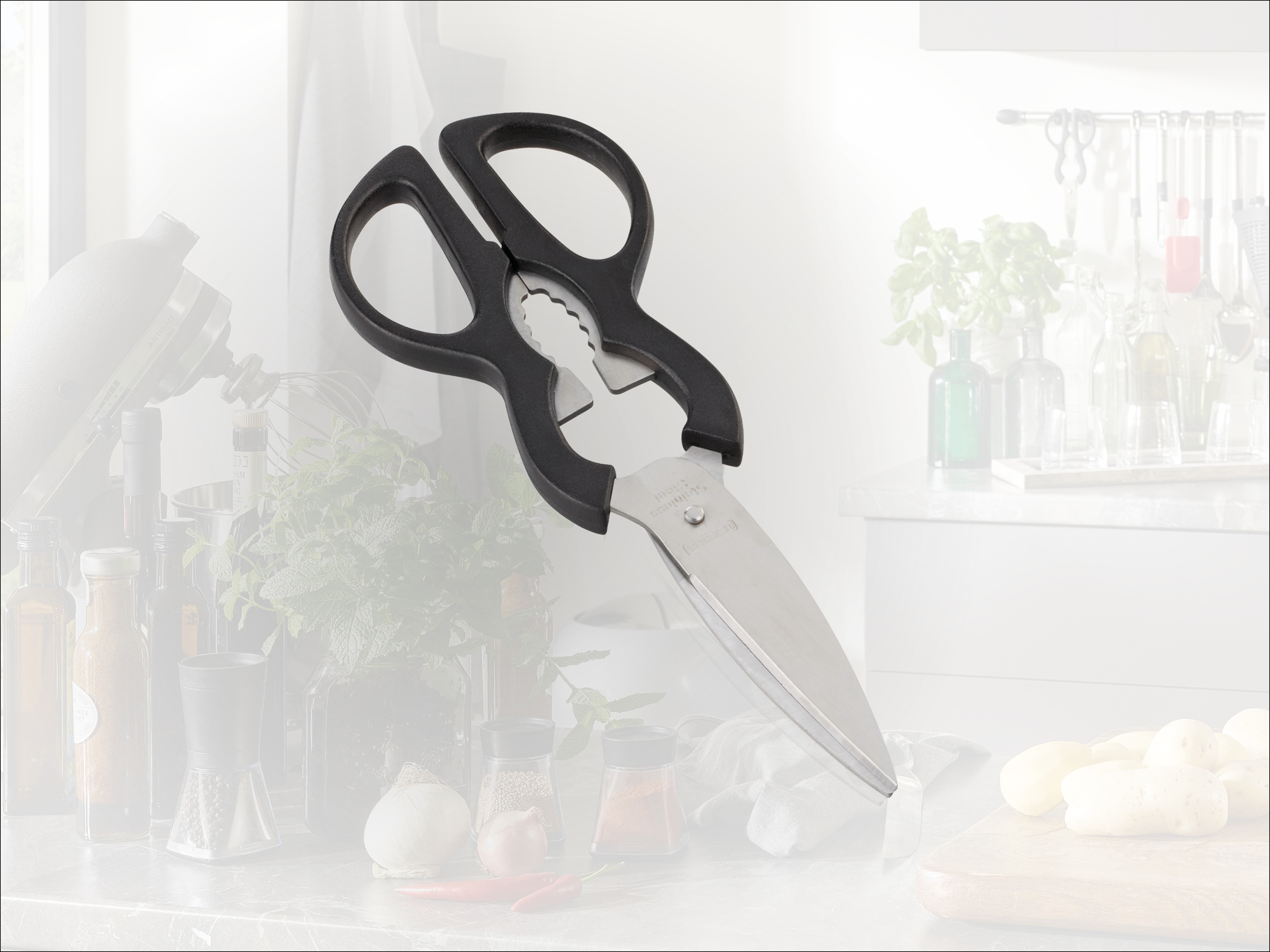 Küchenschere mit schwarzen Griffen und gezackter Klinge auf einer Arbeitsplatte.