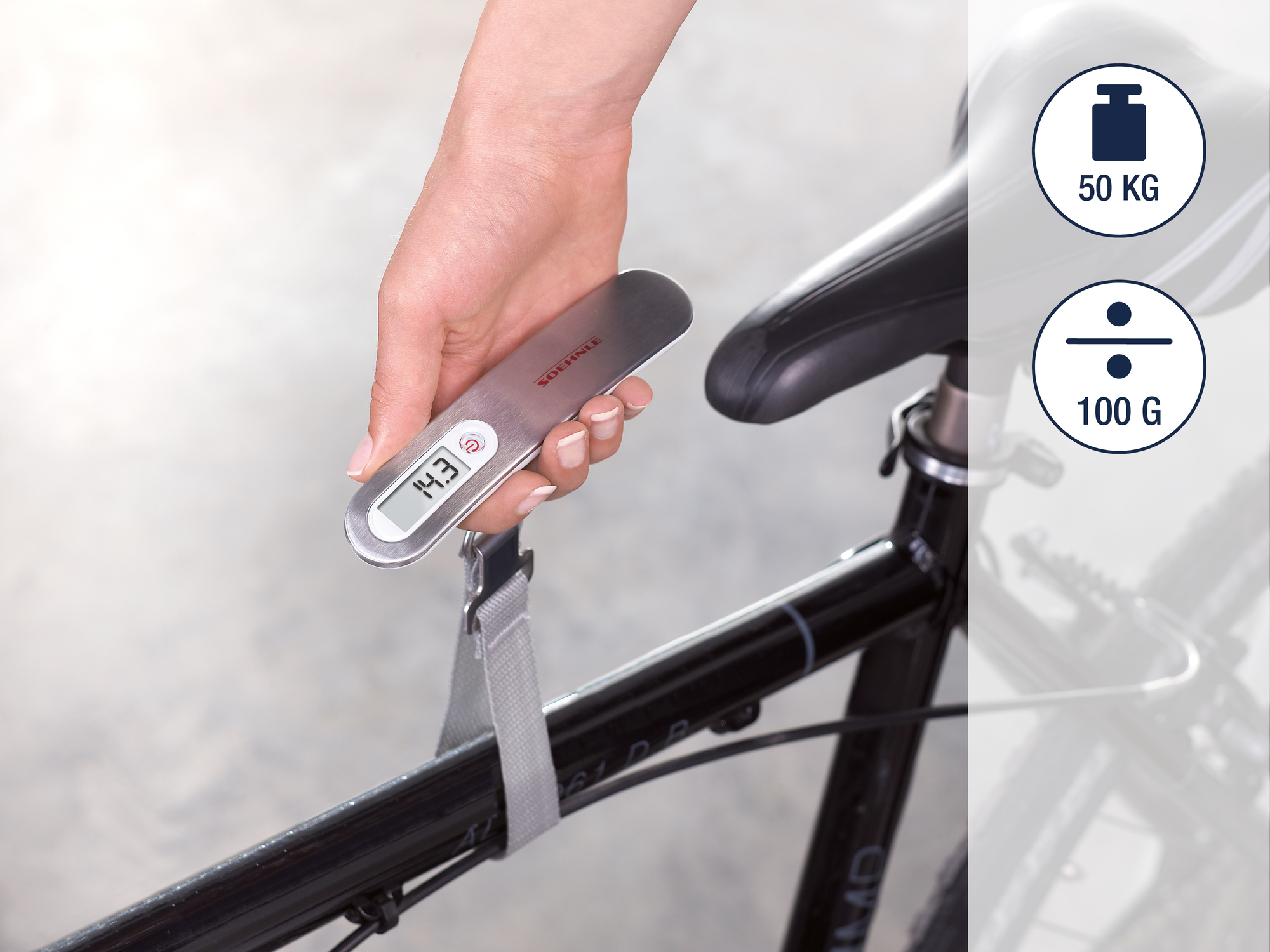 Una mano tiene una bilancia digitale che mostra 14,3 accanto a una sella da bicicletta.