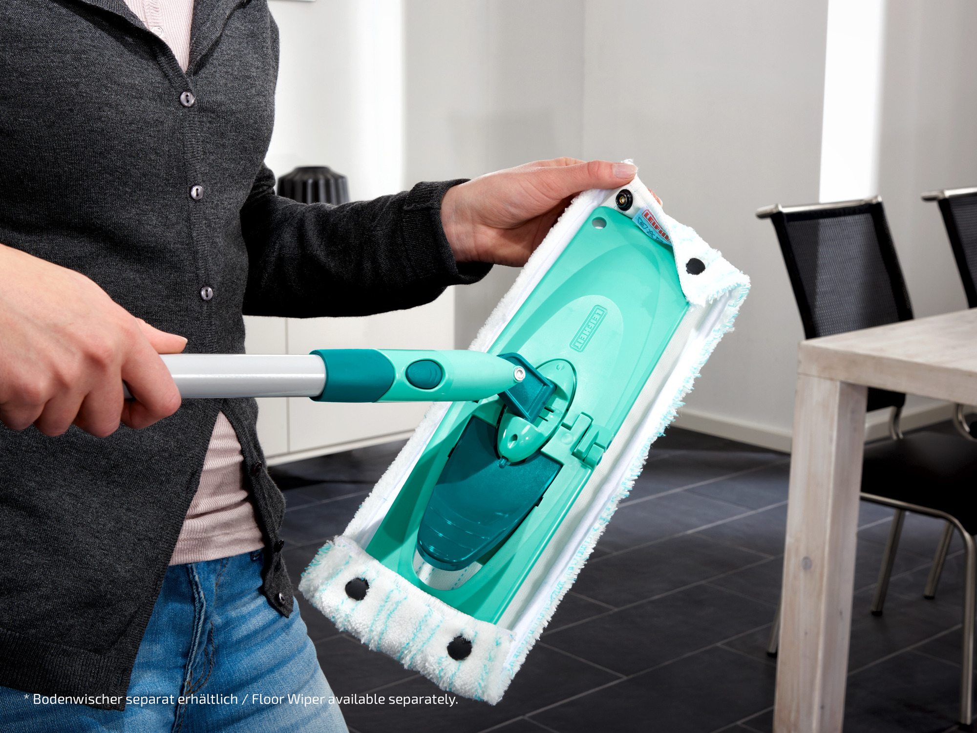 Person hält einen grünen Wischmopp mit einem weißen Bezug und blauen Streifen.