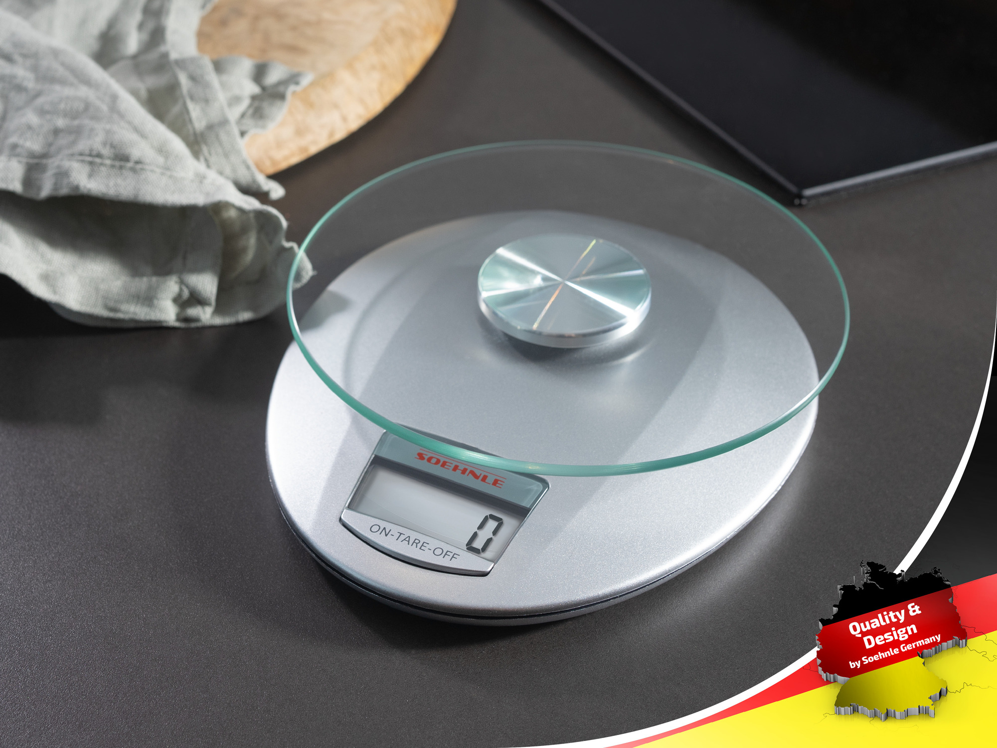Bilancia da cucina argentata con piano in vetro e display digitale su superficie scura.