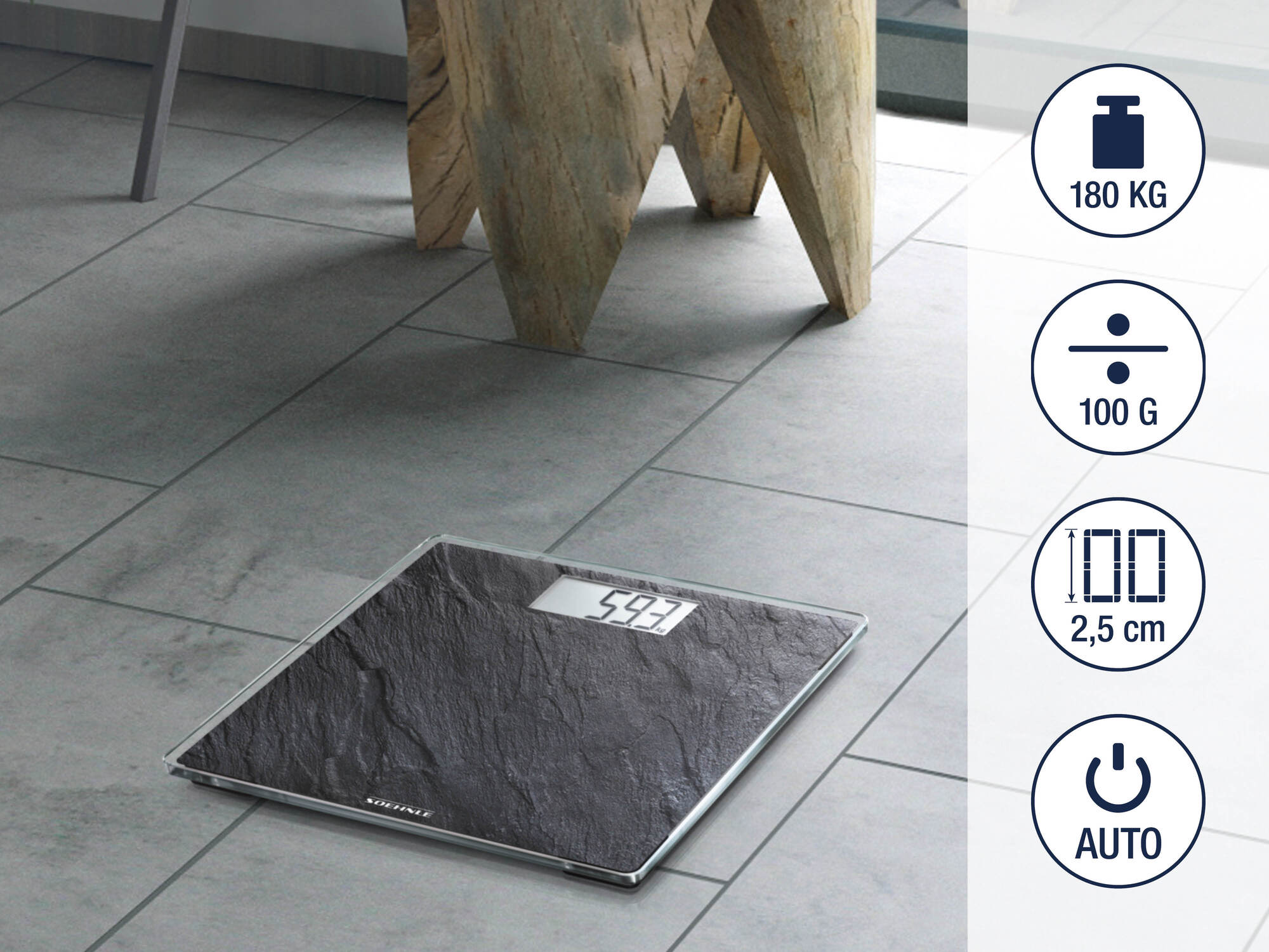 Czarna waga cyfrowa z kamiennym wzorem na szarej podłodze z płytek obok drewnianych nóg mebla.