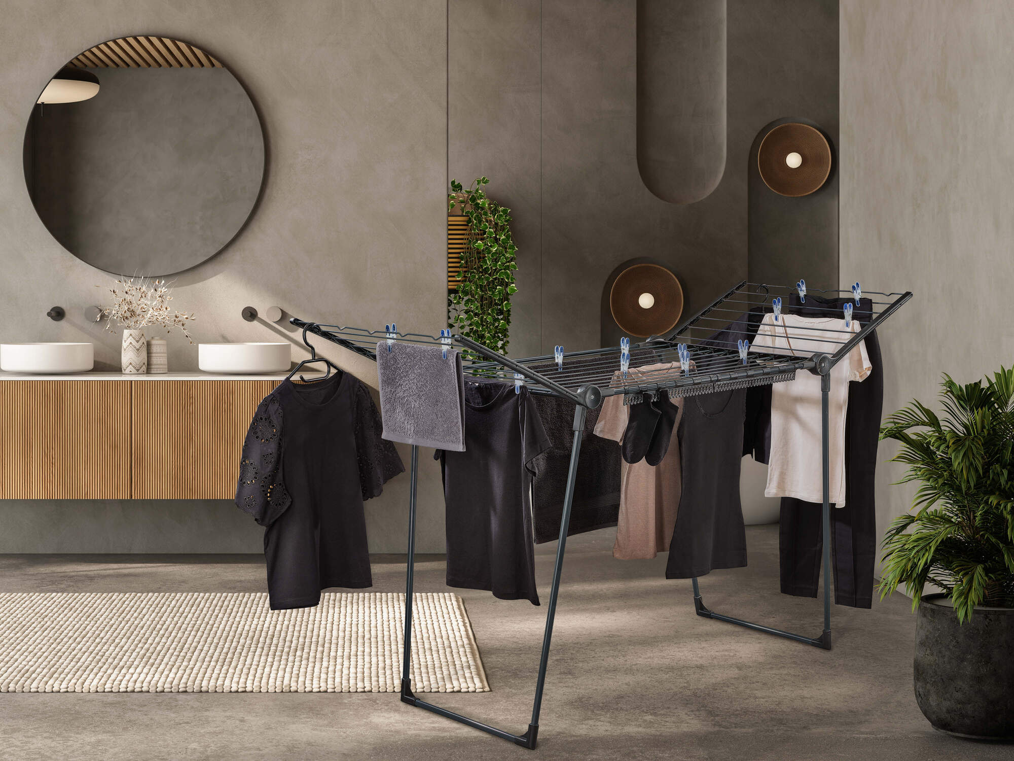 Uno stendibiancheria con vestiti scuri si trova in un bagno moderno.