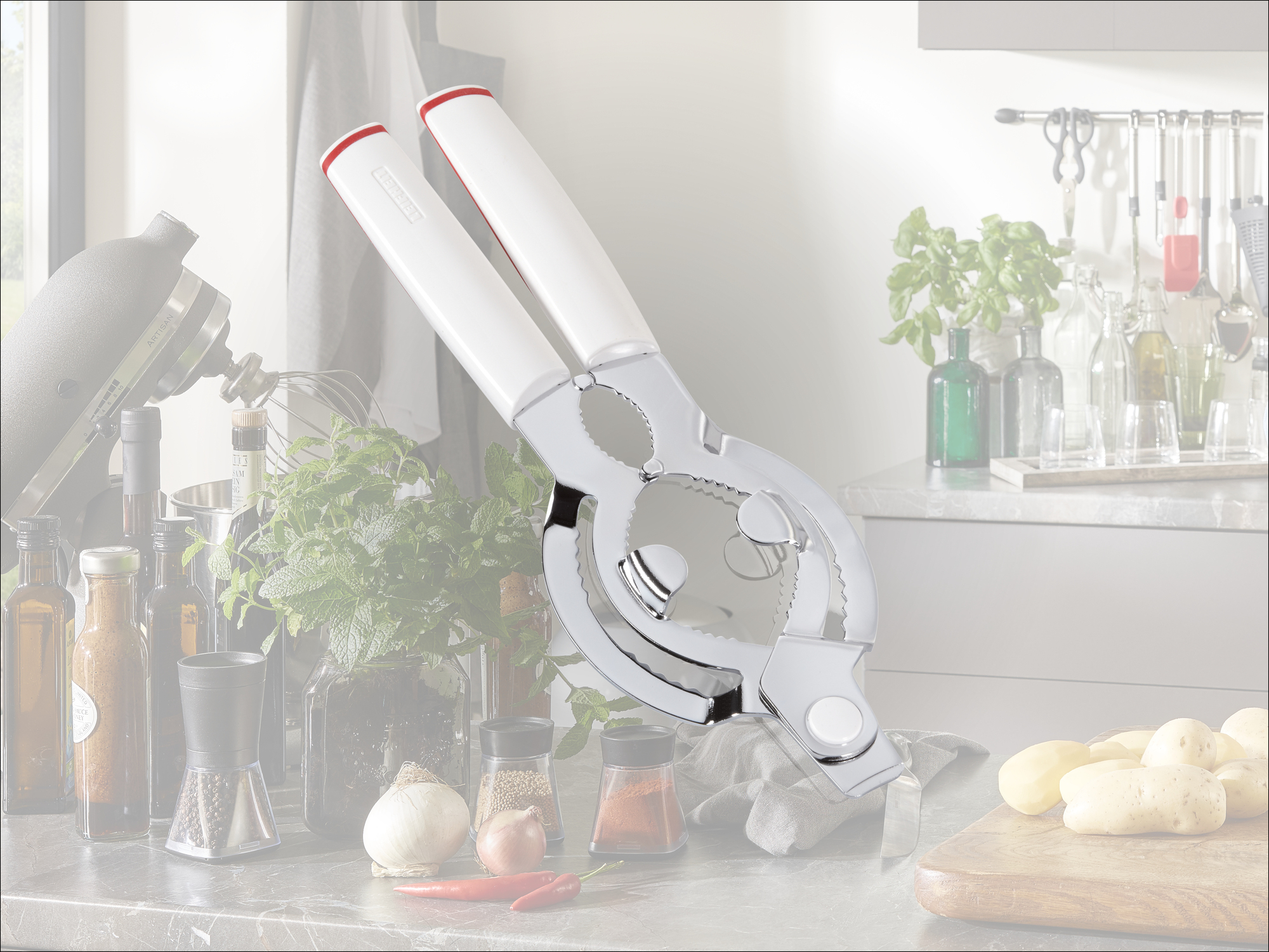 Küchenutensilien mit Dosenöffner, Mixer und Kartoffeln auf der Arbeitsplatte.