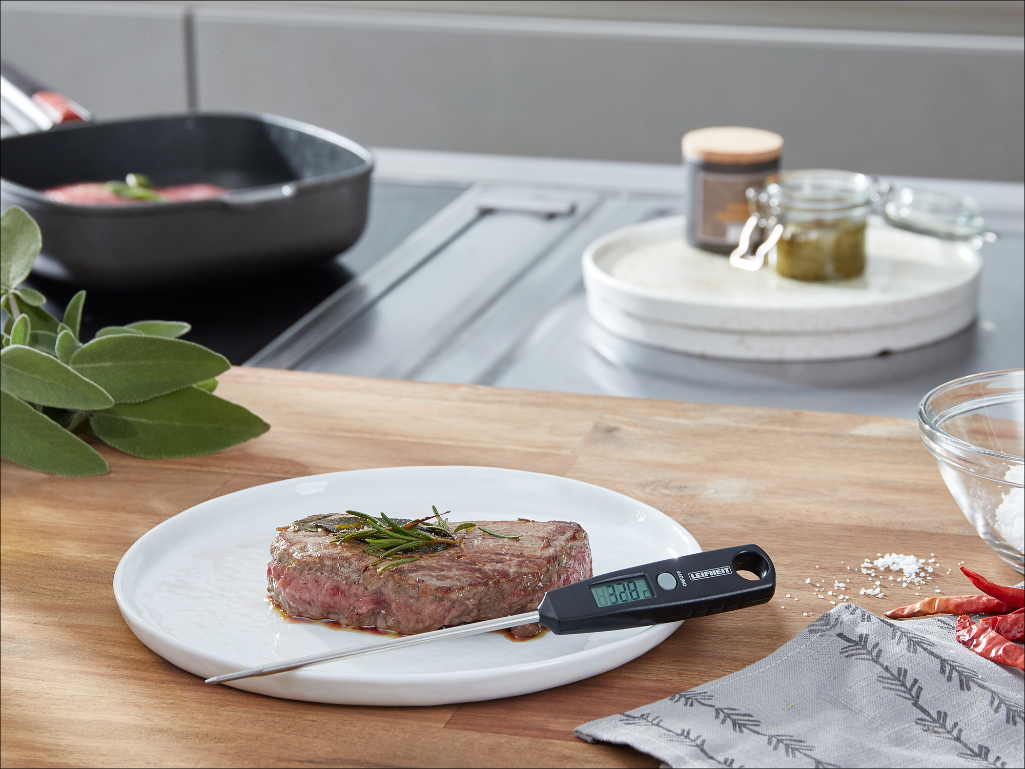Una bistecca al rosmarino viene misurata con un termometro per carne su un piatto.
