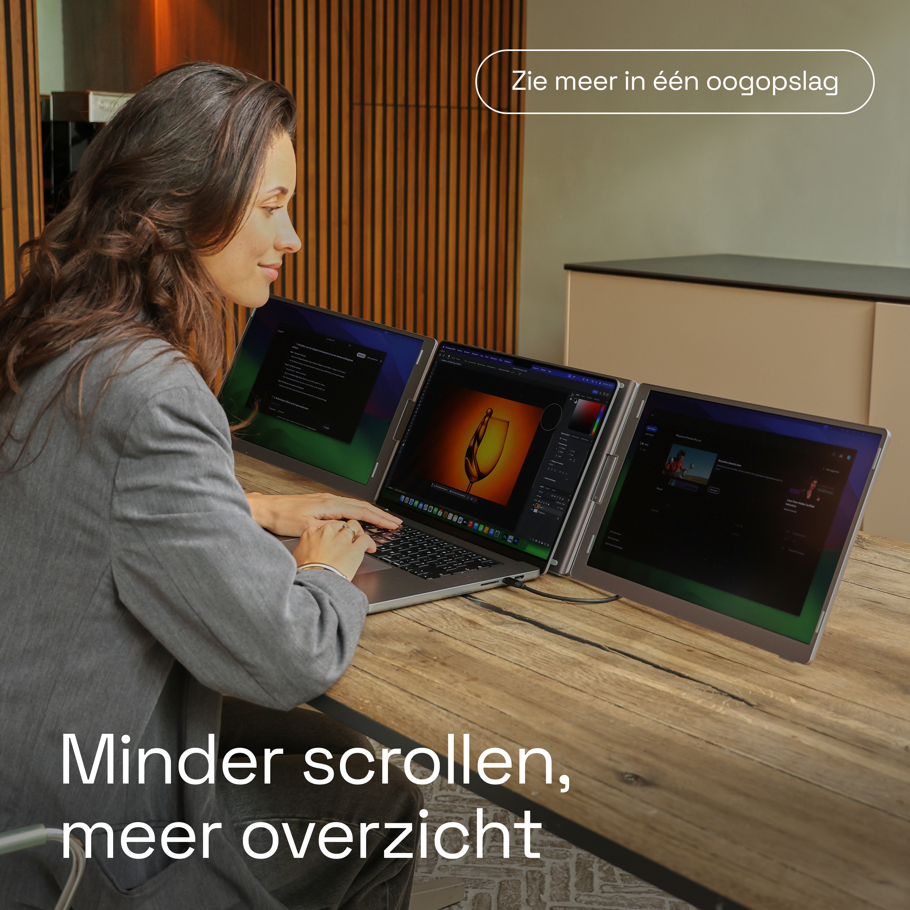 Een vrouw werkt aan een laptop met drie schermen in een moderne kantoorruimte.