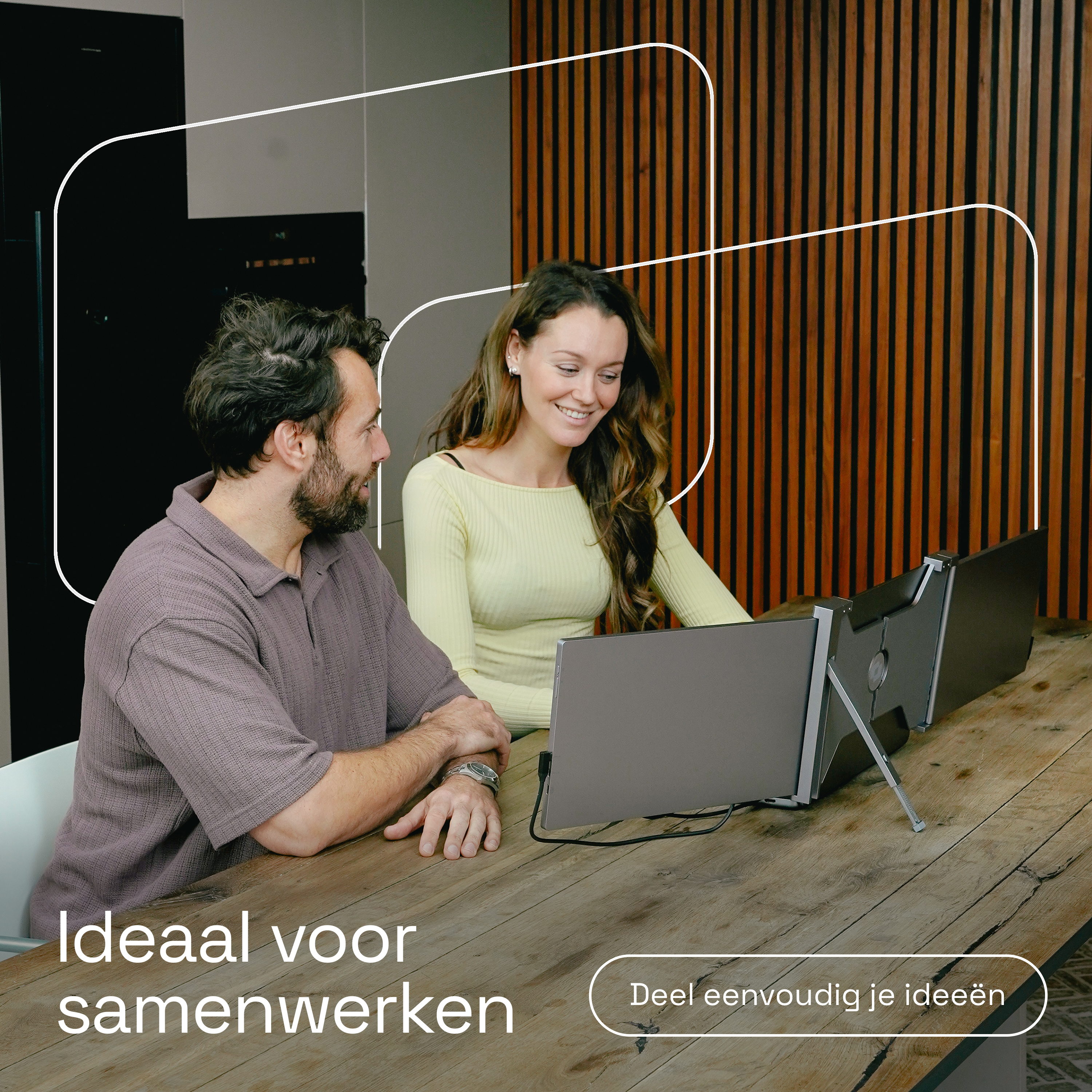 Man en vrouw werken samen aan een laptop en twee externe monitoren.