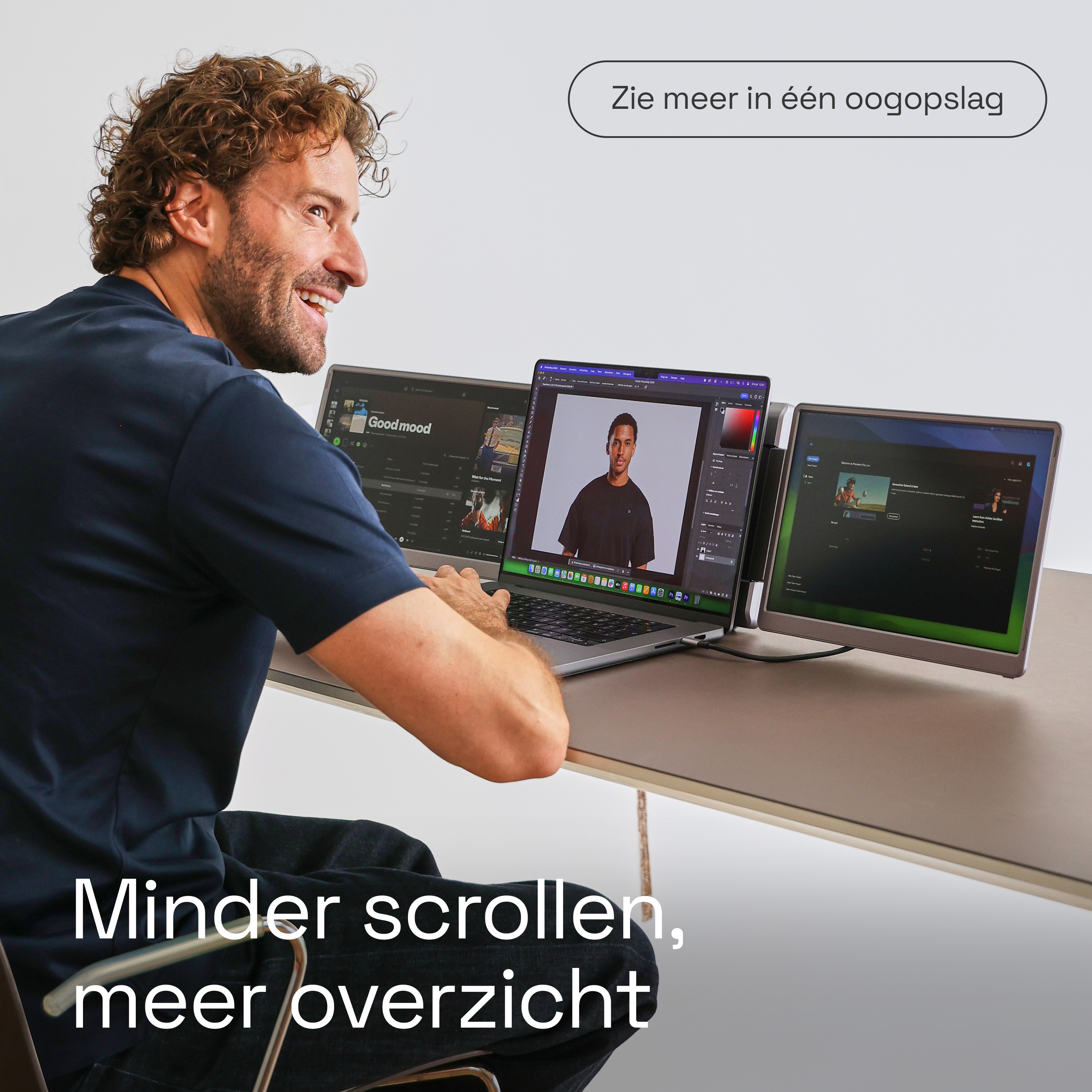 A man with curly hair sits at a desk with three monitors.