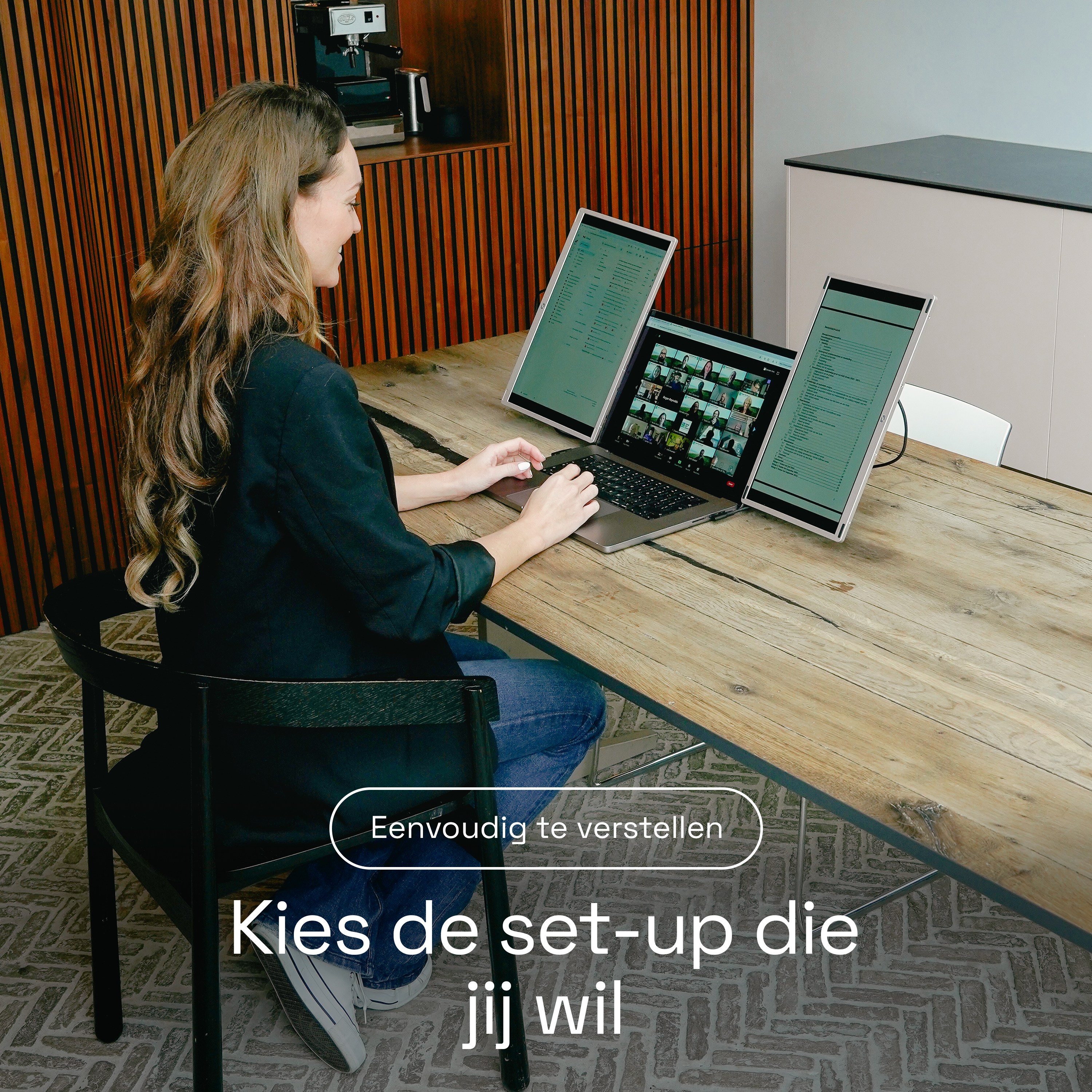 Femme sur un ordinateur portable avec trois écrans dans un bureau lambrissé.