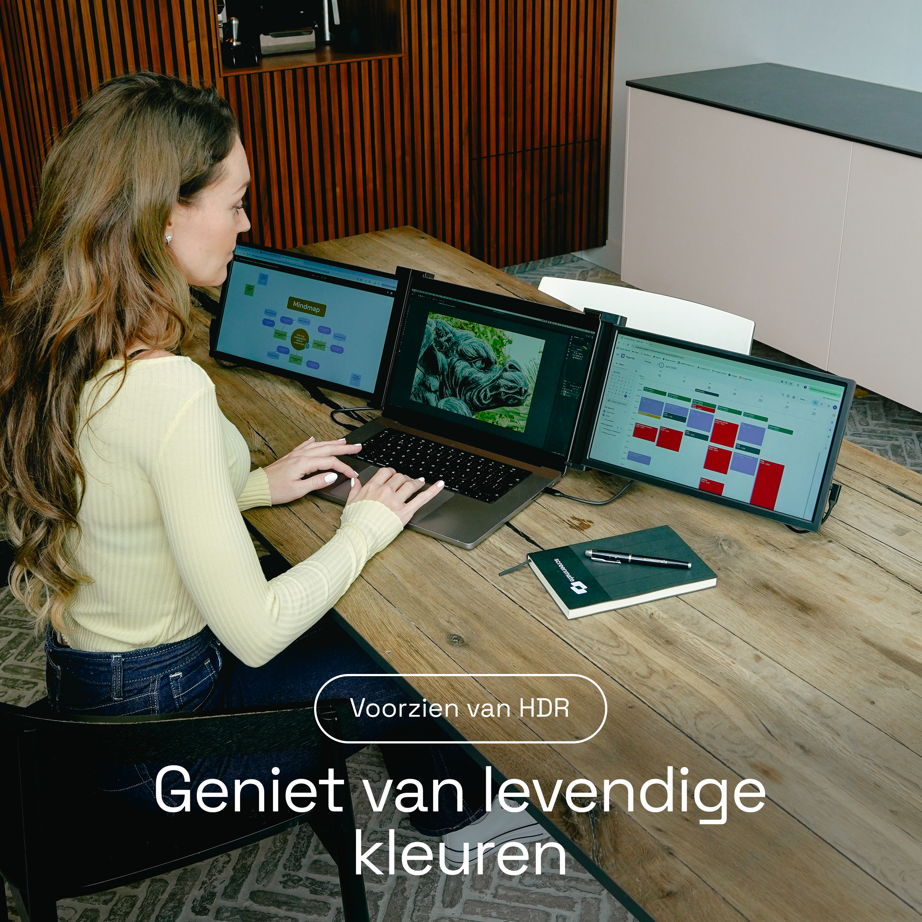 Een vrouw werkt op een laptop met drie schermen. Ze draagt een geel topje.