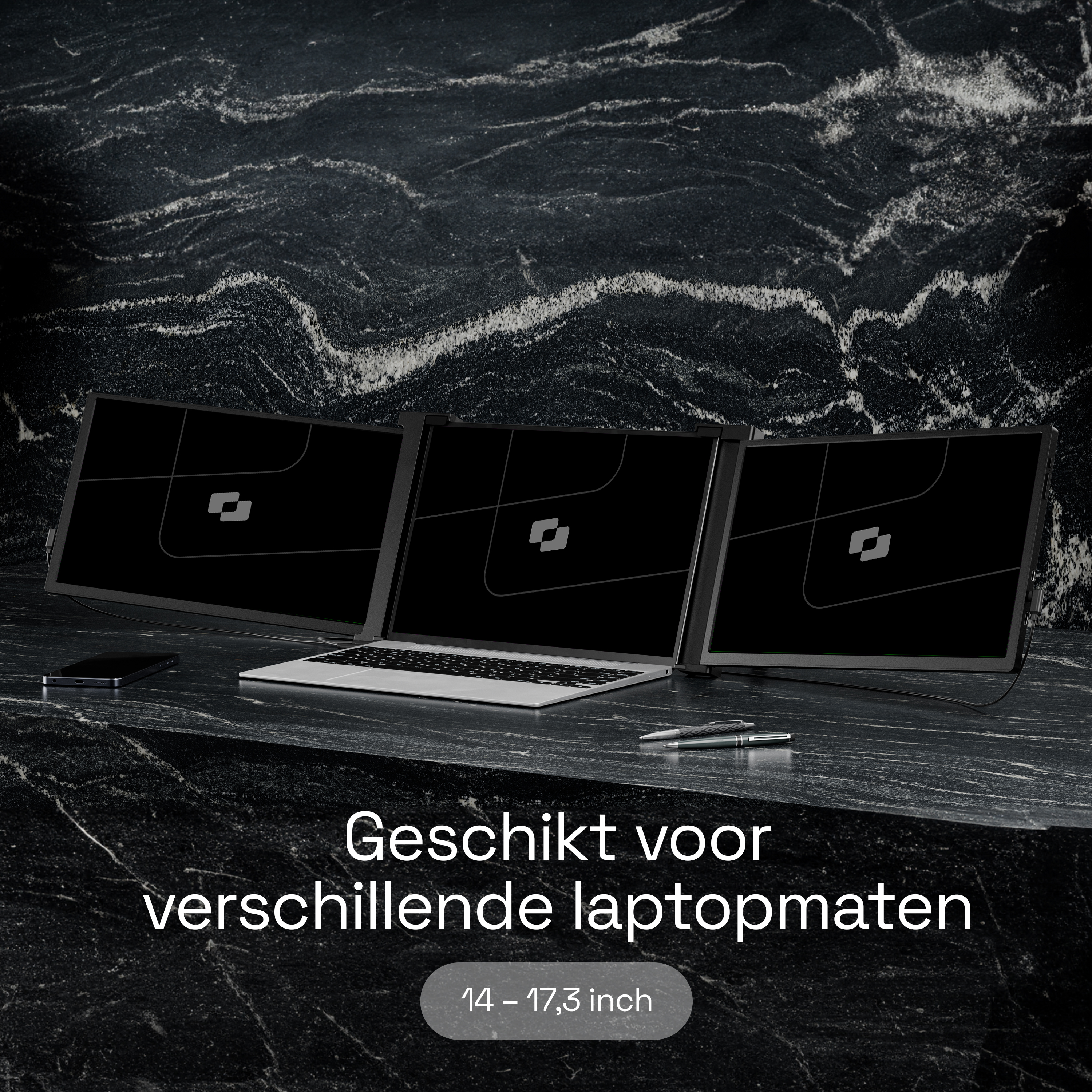 Drie monitoren, laptop, telefoon en pennen op donker marmer.