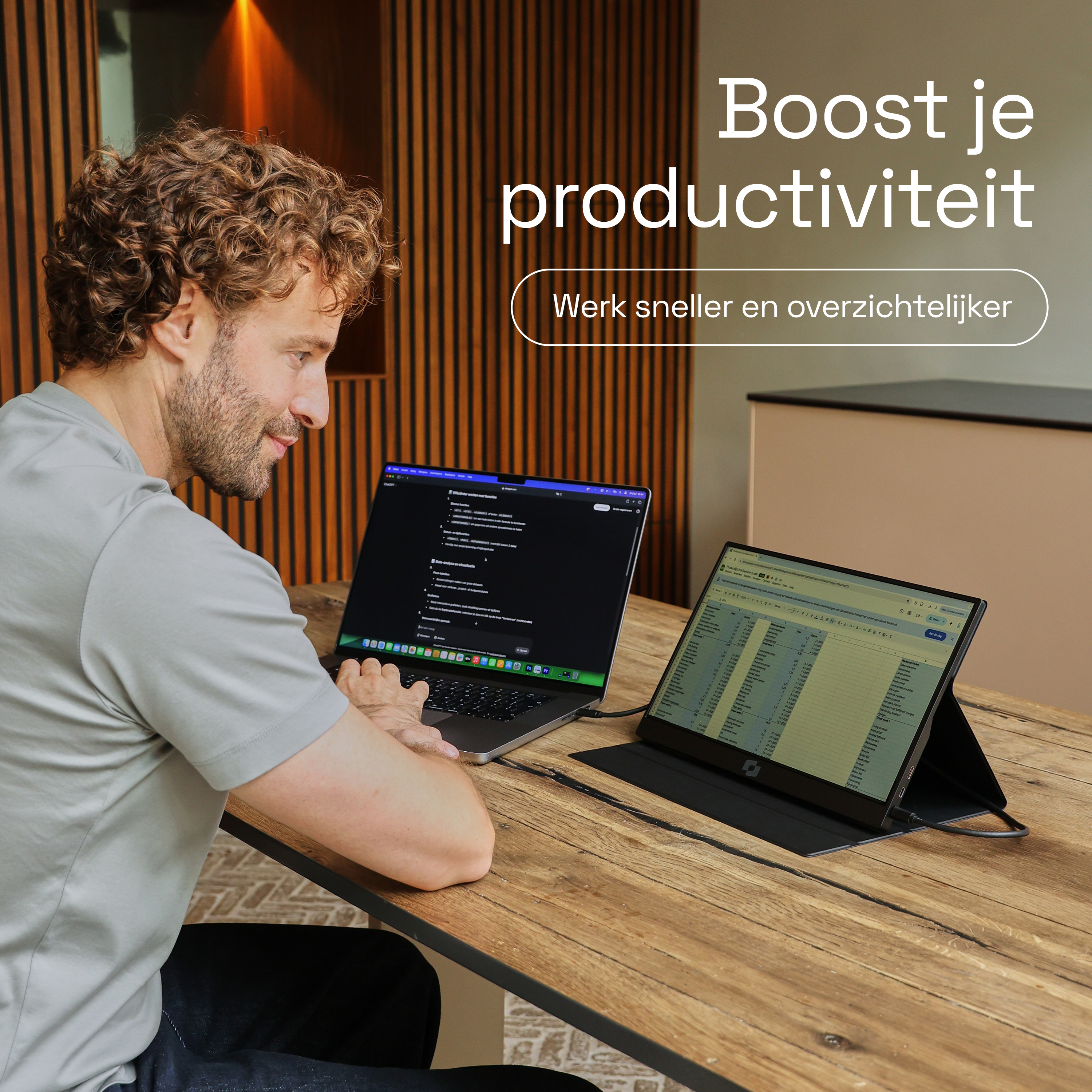 Man werkt met laptop en tweede scherm op houten tafel.