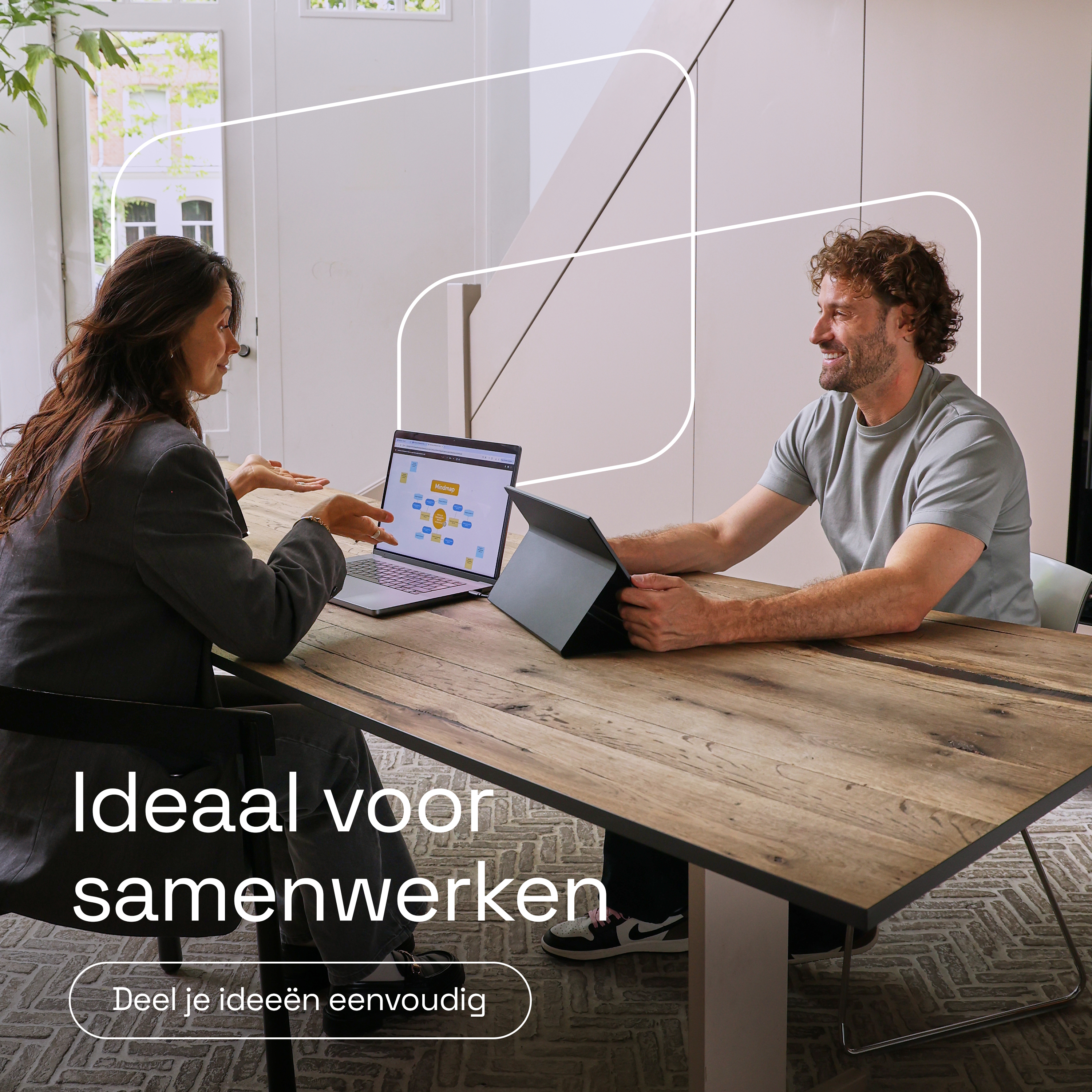 Een man en vrouw werken samen aan een houten tafel met laptops.