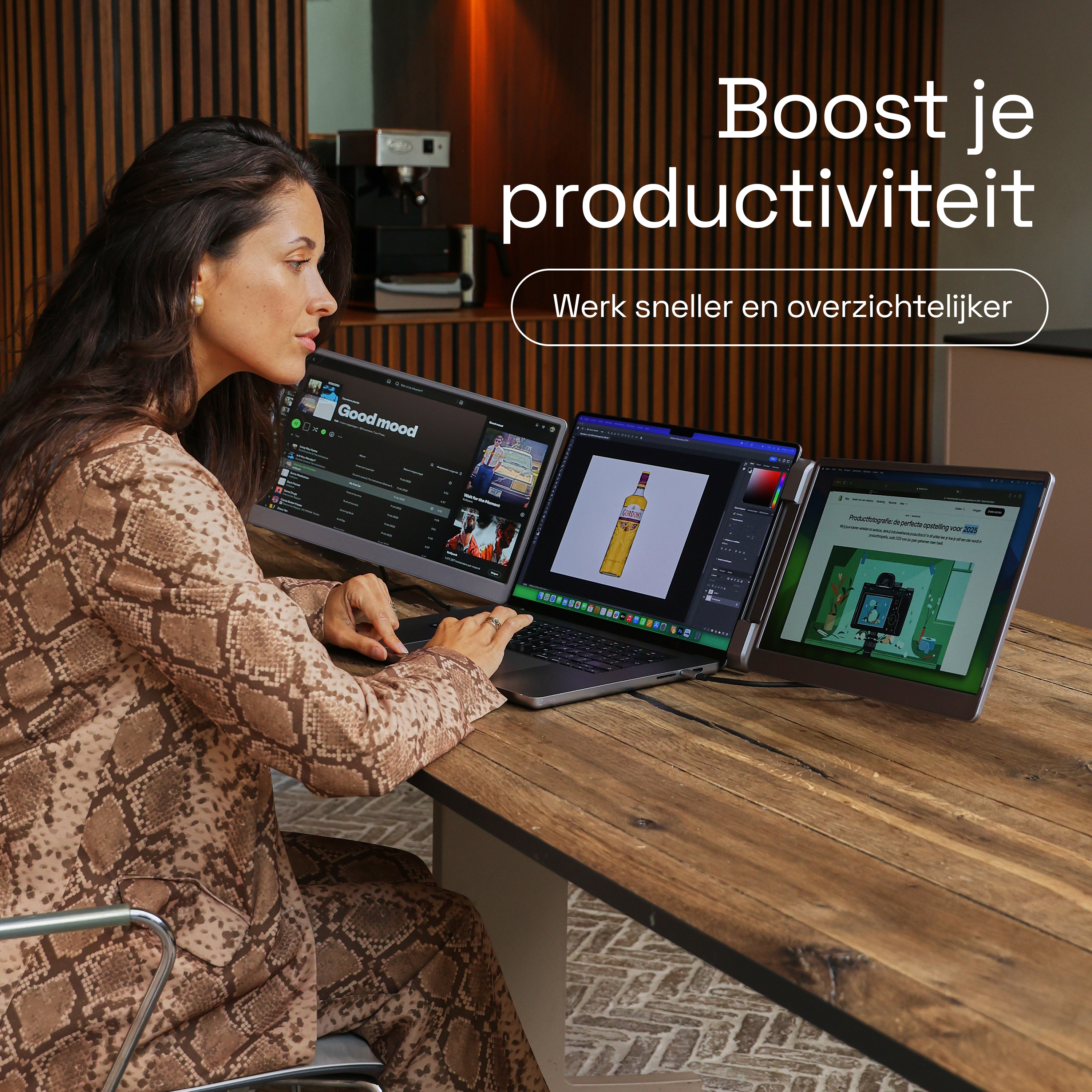 Une femme travaille à un bureau avec trois moniteurs. L'un affiche Spotify, l'autre Photoshop et le troisième une page web.