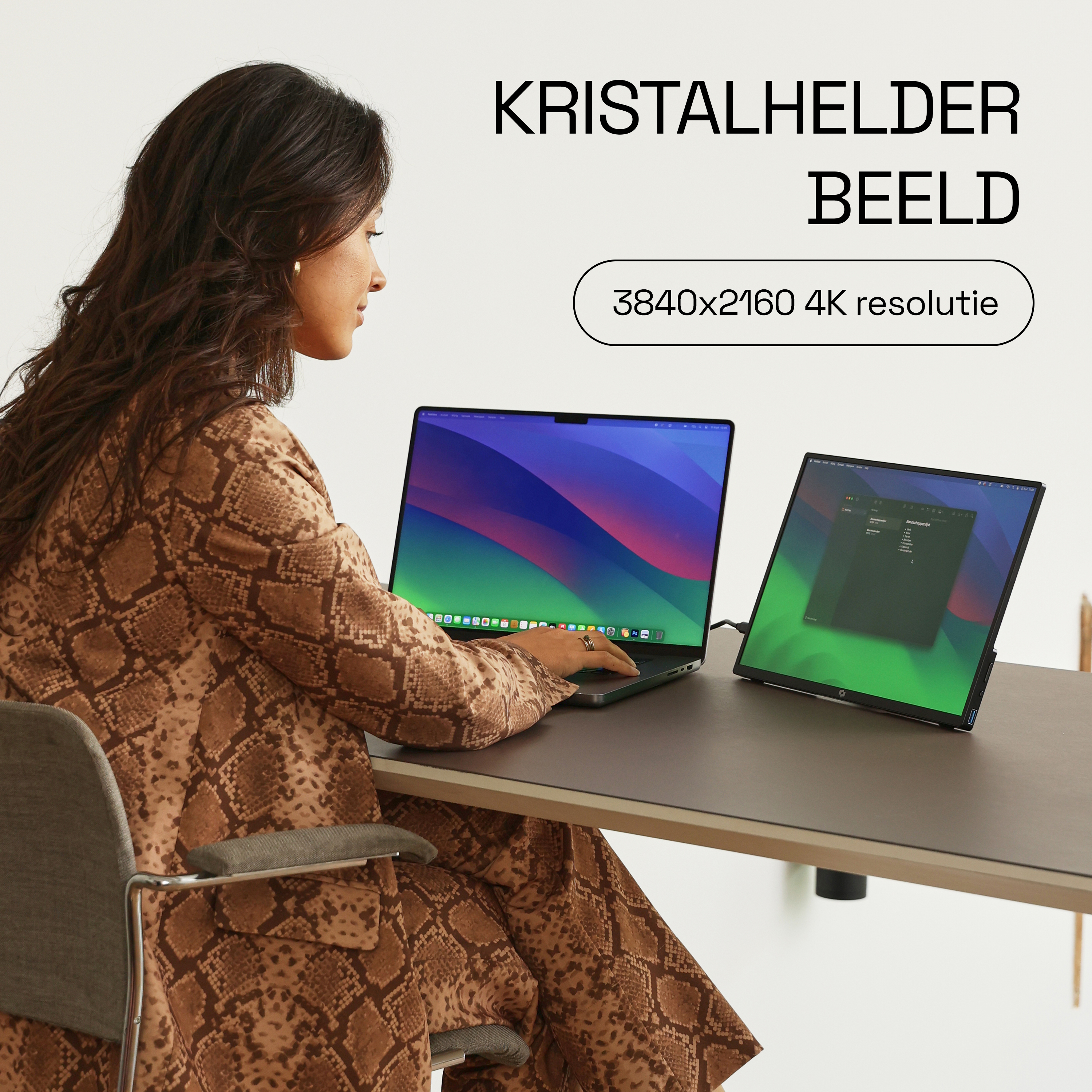 Een vrouw in een bruine slangenhuid outfit werkt op een laptop en externe monitor.