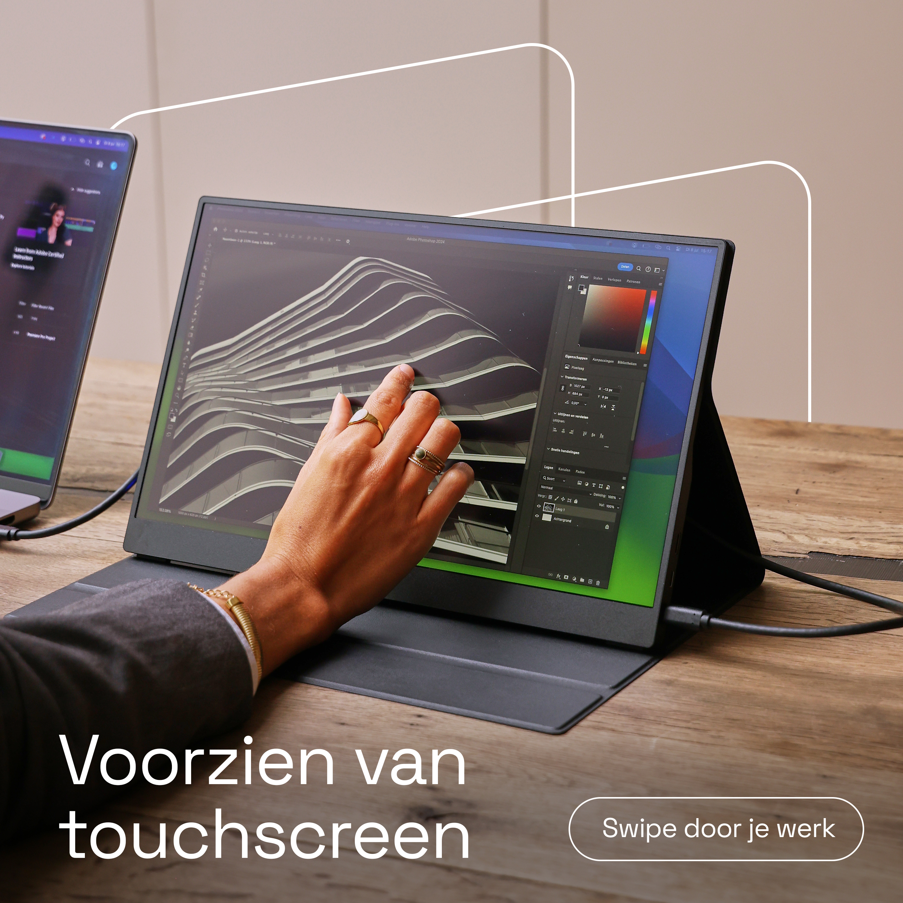 Une main touche un écran tactile affichant Photoshop. Un ordinateur portable est à côté.