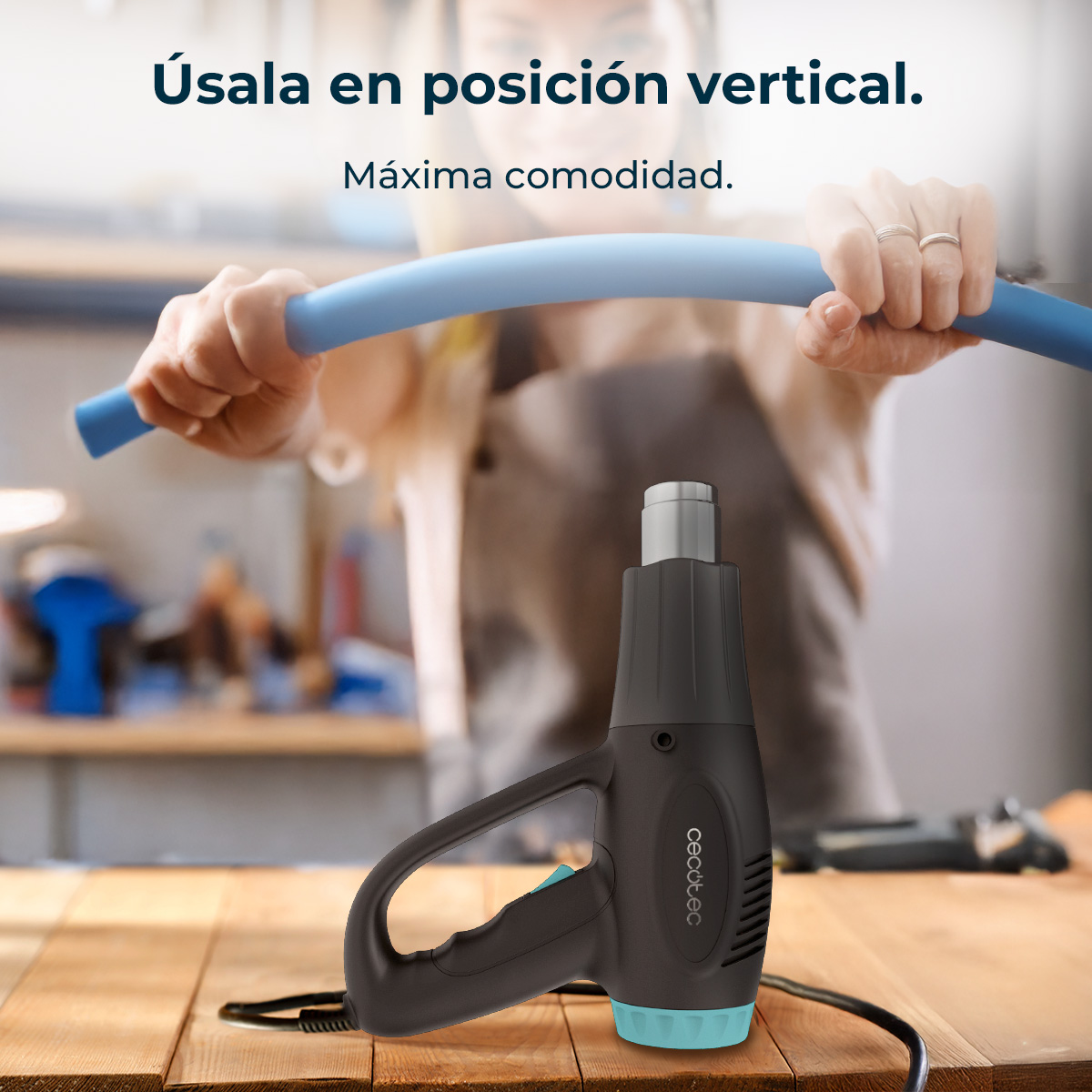 Pistola termica nera con accento blu su tavolo di legno. Mani piegano tubo blu.
