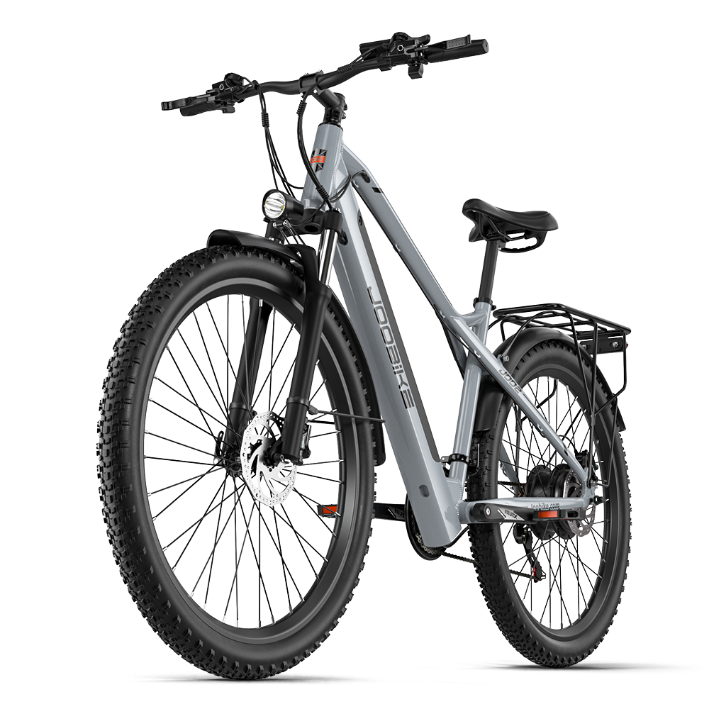 Ein graues E-Bike mit breiten Reifen, Federung, Gepäckträger und Scheinwerfer.