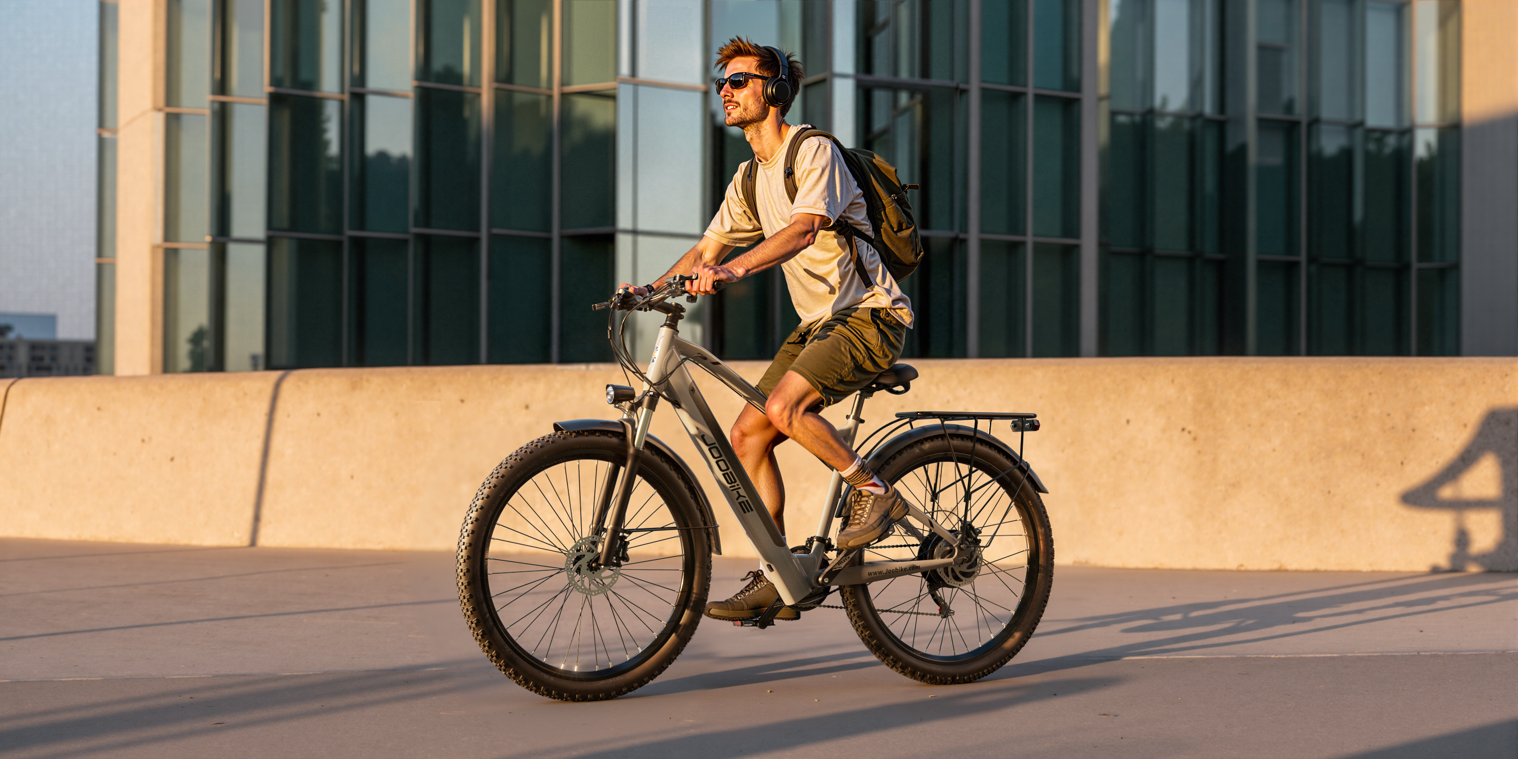 Ein Mann mit Kopfhörern fährt mit einem E-Bike an einem Gebäude entlang.