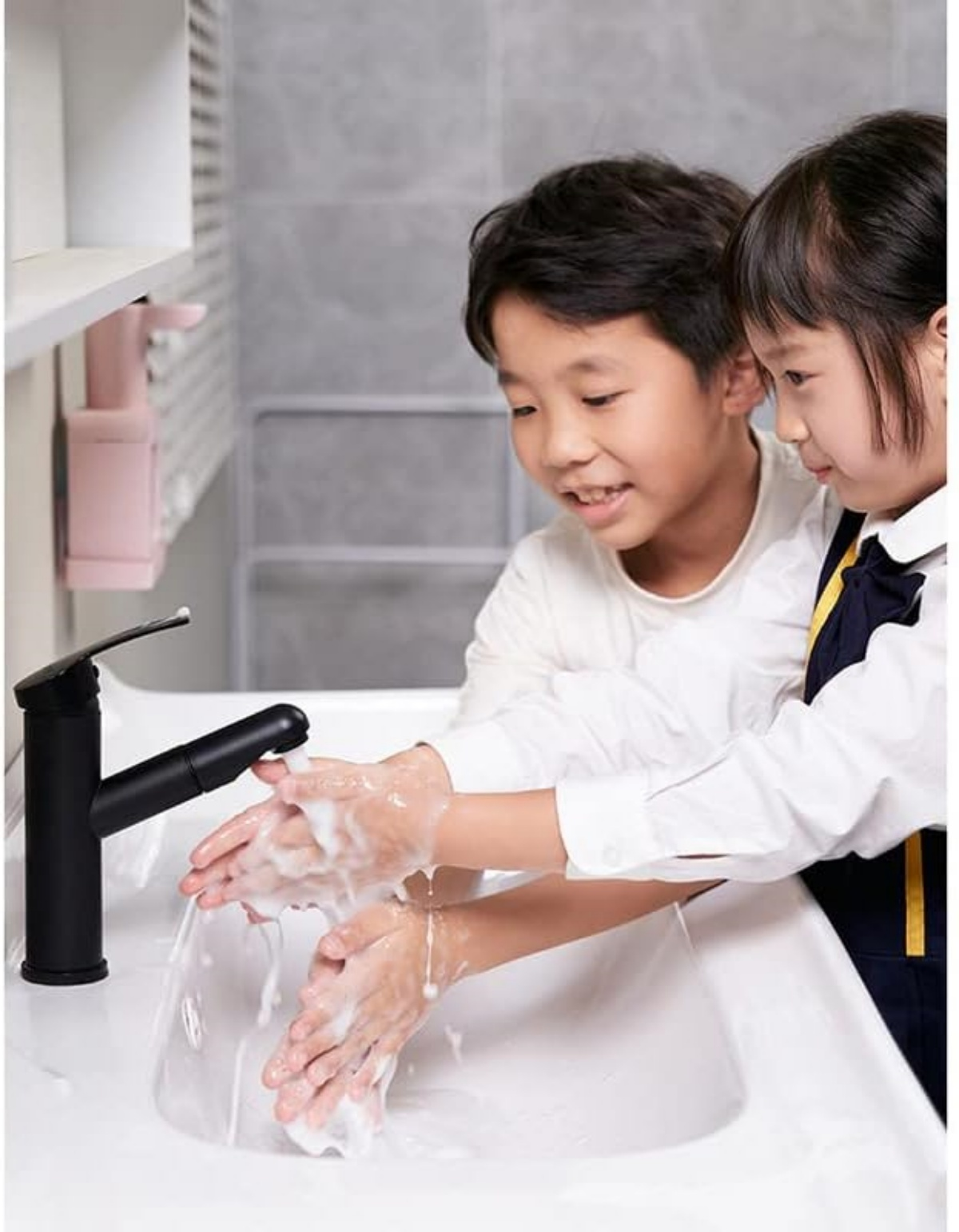 Zwei Kinder waschen sich die Hände mit Seife und Wasser in einem weißen Waschbecken.