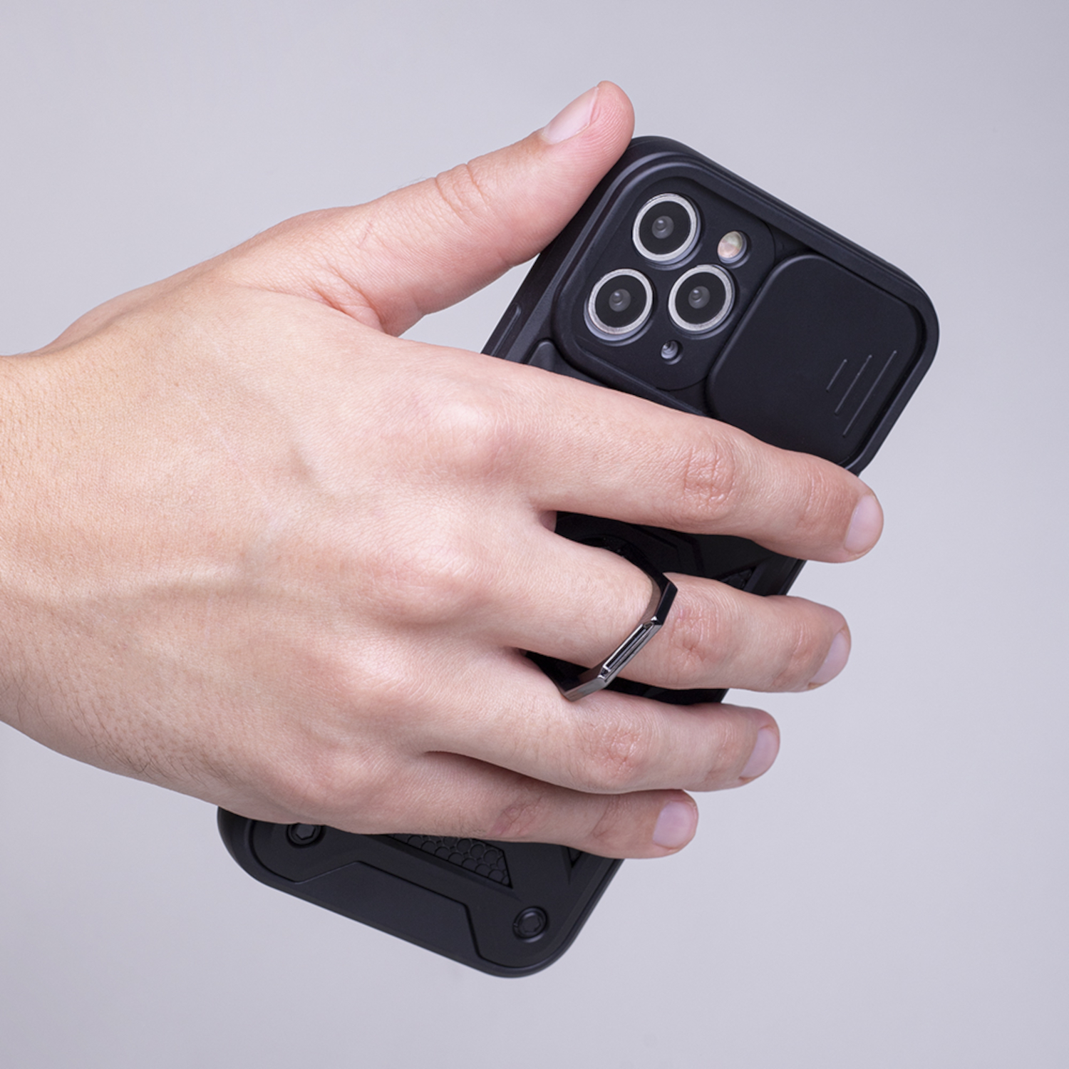 Eine Hand hält ein schwarzes Handy mit einer Ringhalterung am Finger.