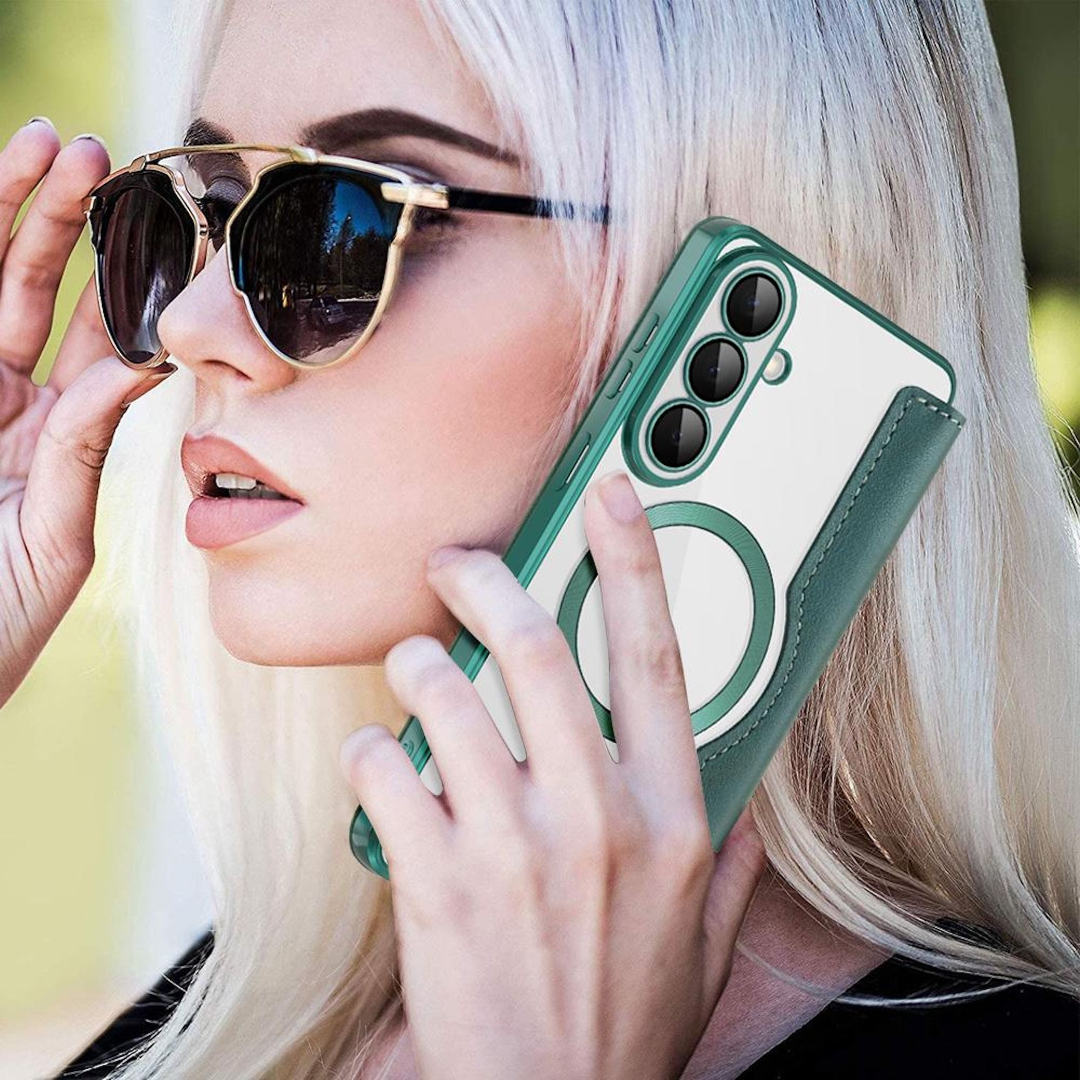Mujer rubia con gafas de sol sostiene un teléfono con funda verde.