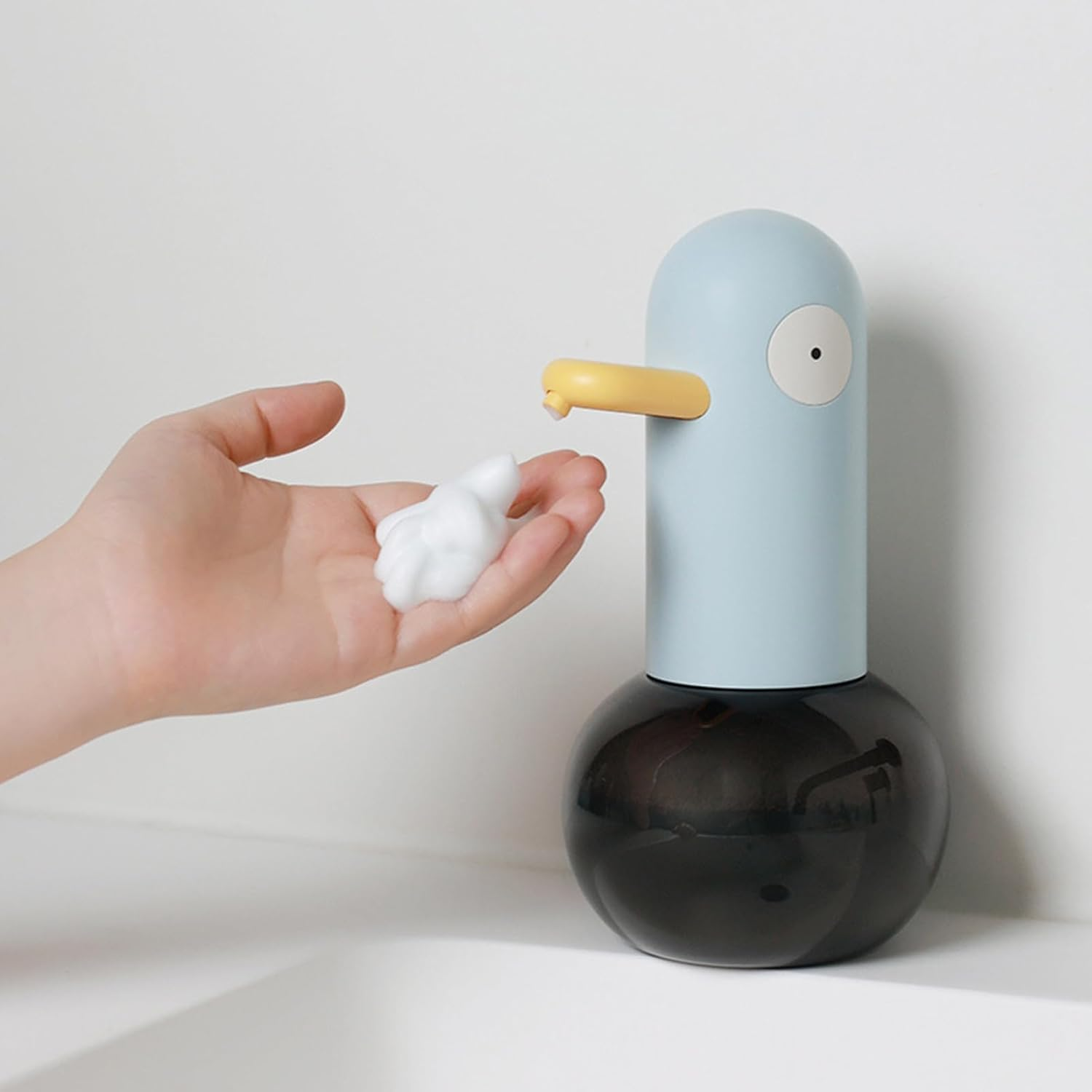 Eine Hand fängt Schaum von einem blauen Enten-Seifenspender auf.