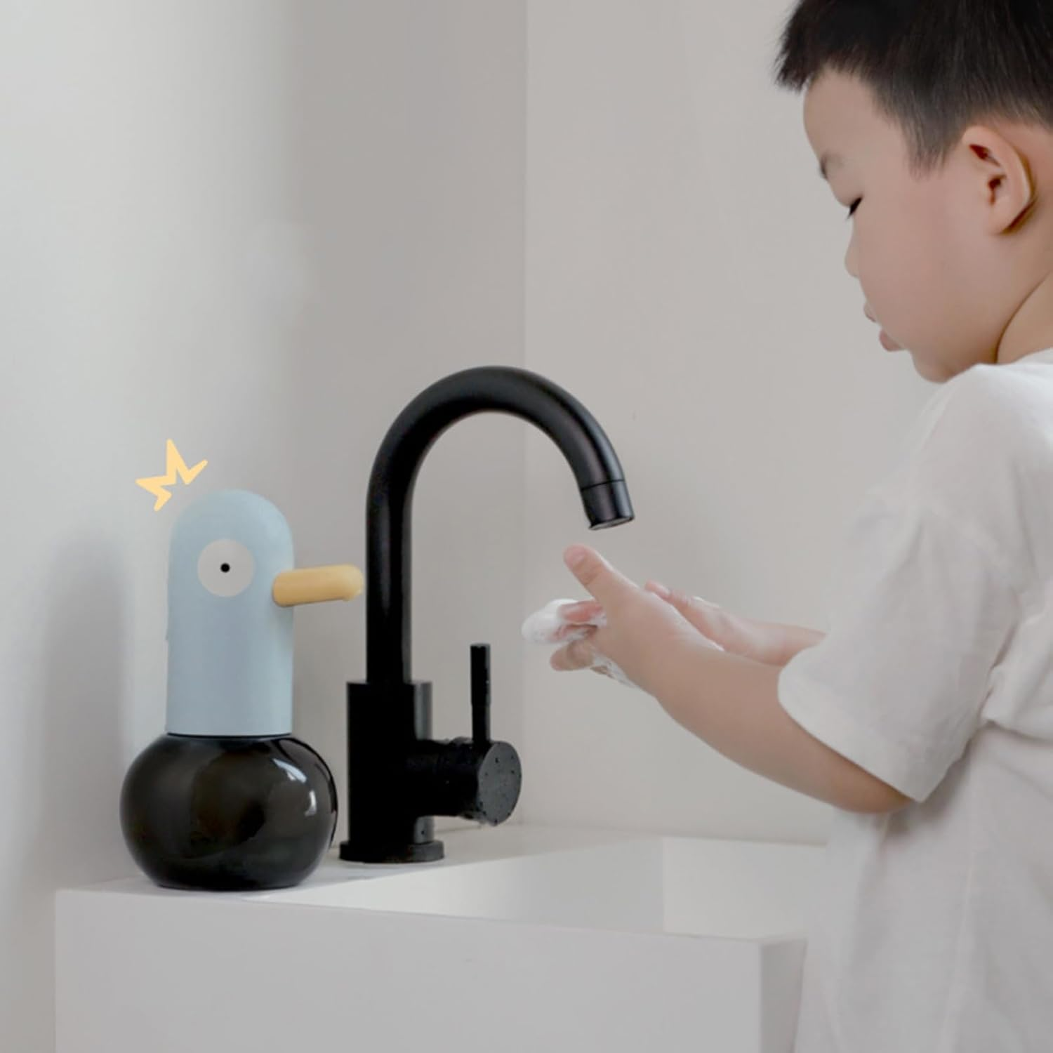 Ein Junge wäscht sich die Hände an einem Wasserhahn neben einem blauen Seifenspender in Entenform.