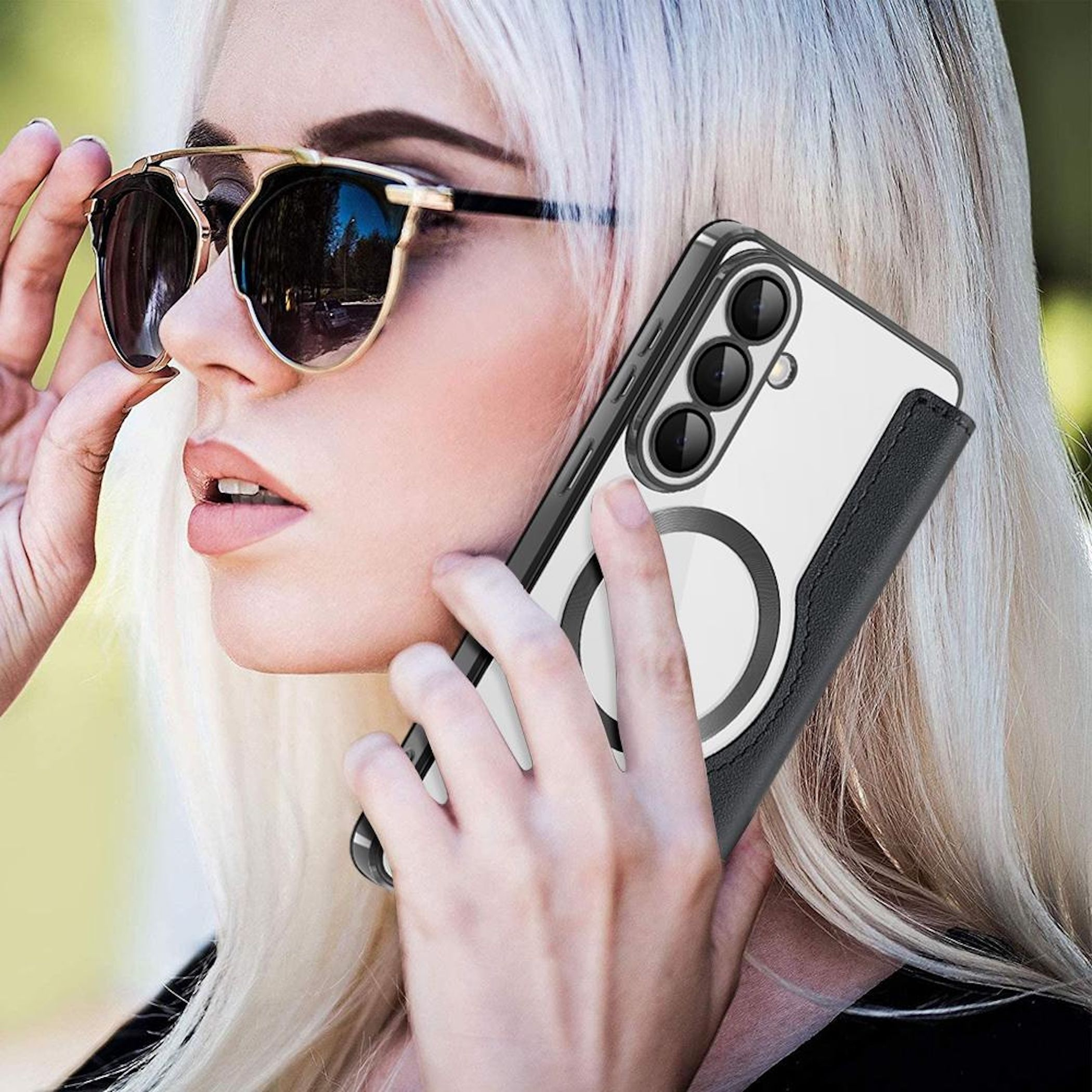 Una mujer con cabello rubio y gafas de sol sostiene un teléfono con funda.
