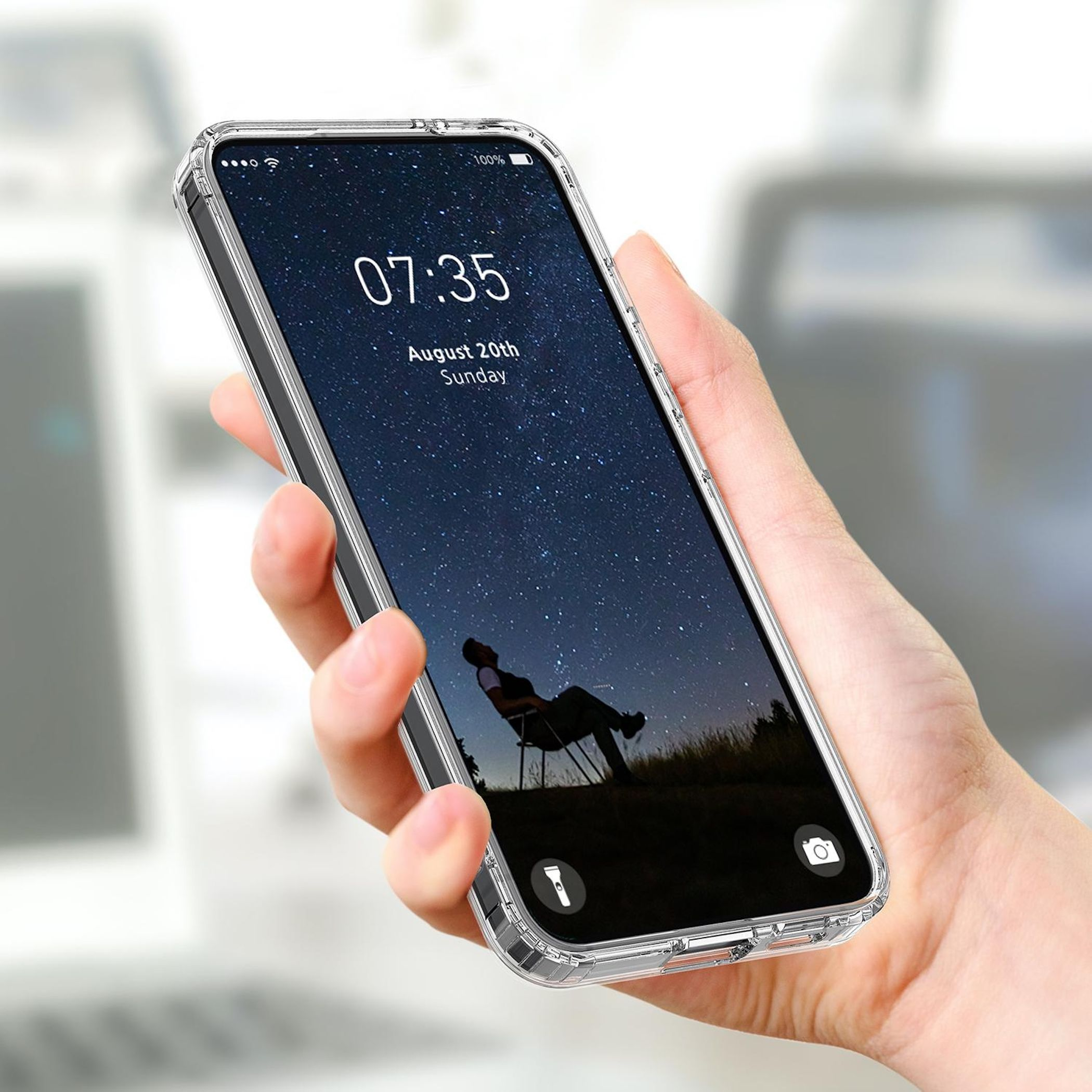 Eine Hand hält eine durchsichtige Handyhülle mit Sternenhimmel-Hintergrund und einer sitzenden Person.