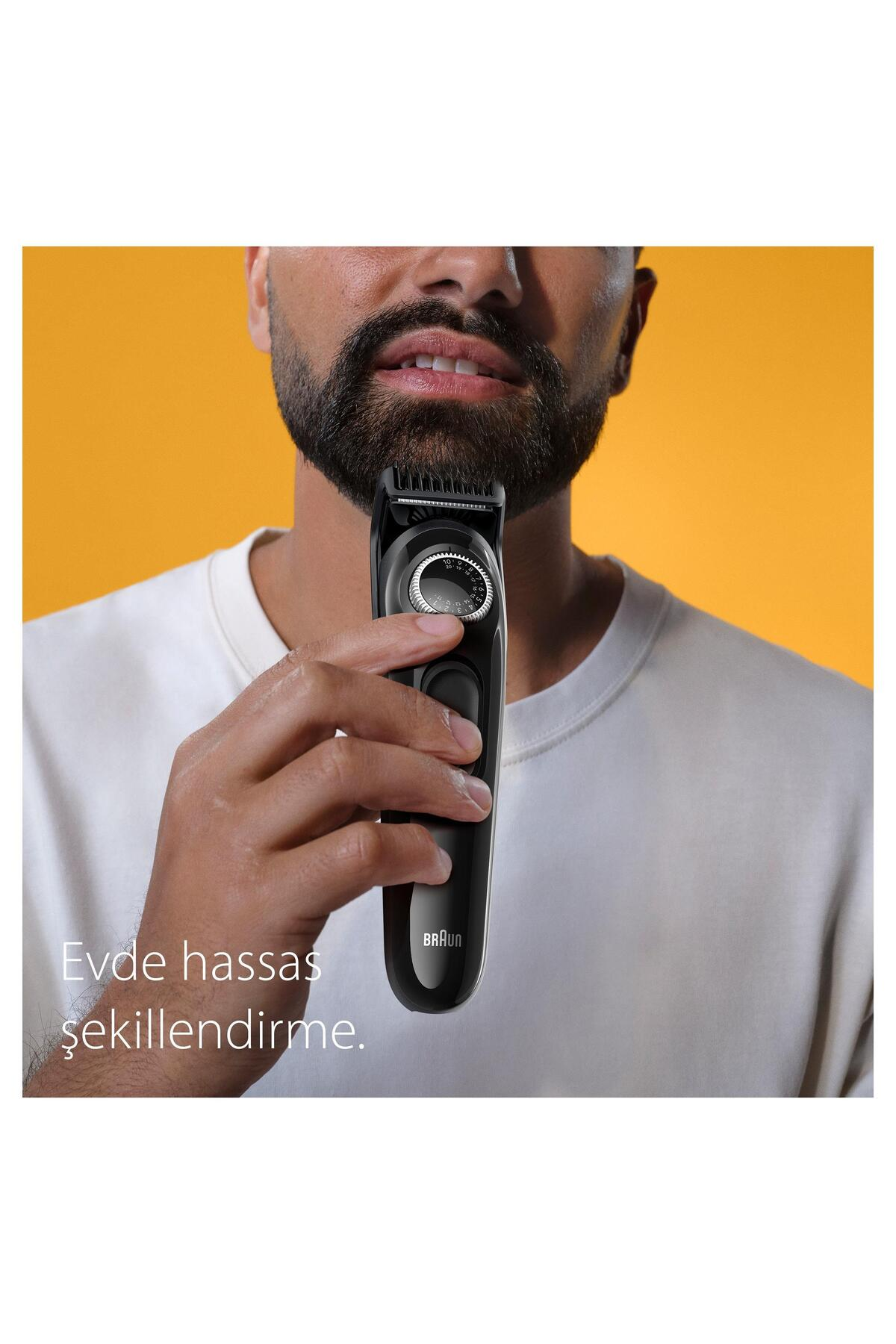 Erkek sarı fon önünde siyah düzelticiyle sakalını şekillendiriyor.