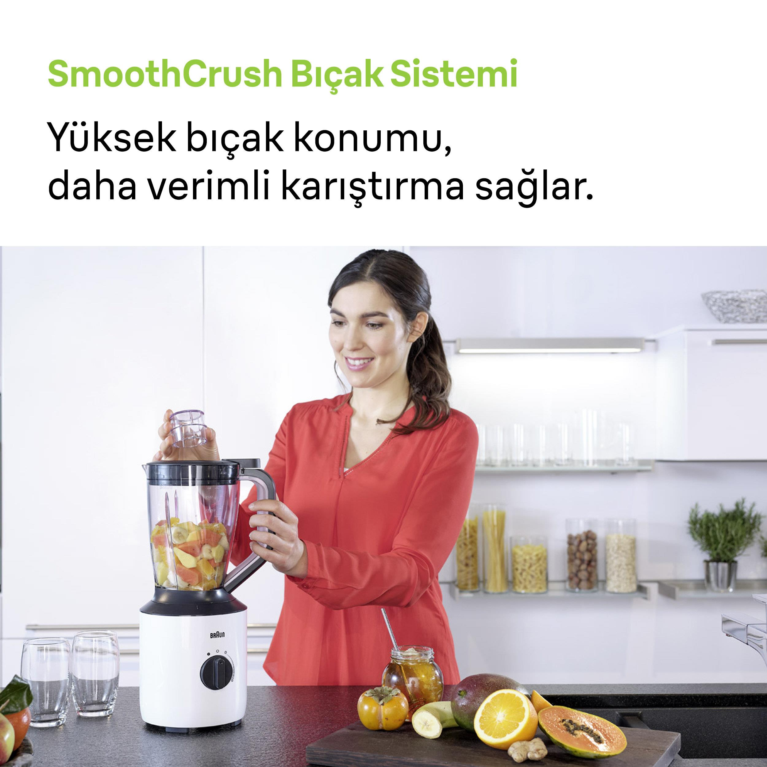 Kırmızı üstlü bir kadın blender'a meyve ekliyor.