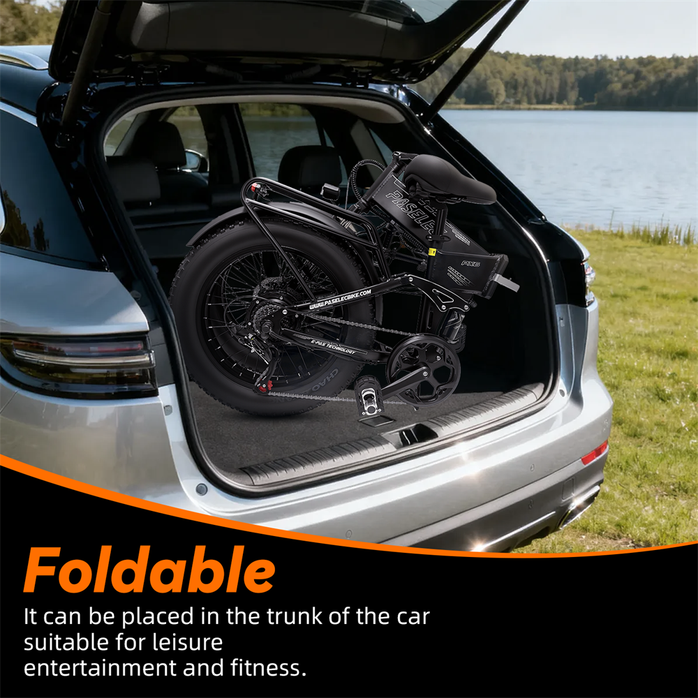 Czarny rower składany w bagażniku samochodu, nad jeziorem.