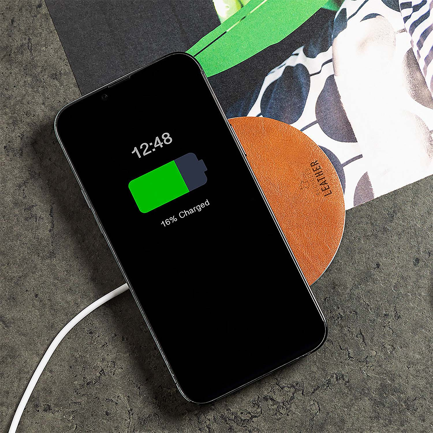 Smartphone negro cargando en posavasos naranja con cable blanco.