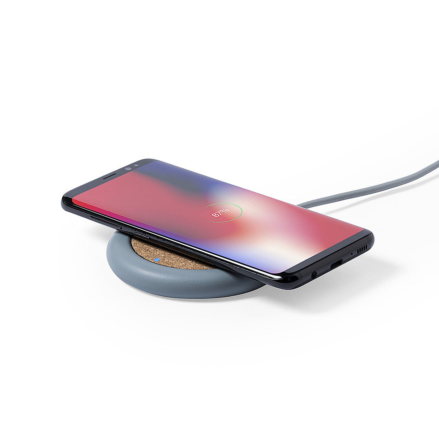 Un smartphone al 87% de carga en un cargador inalámbrico gris.