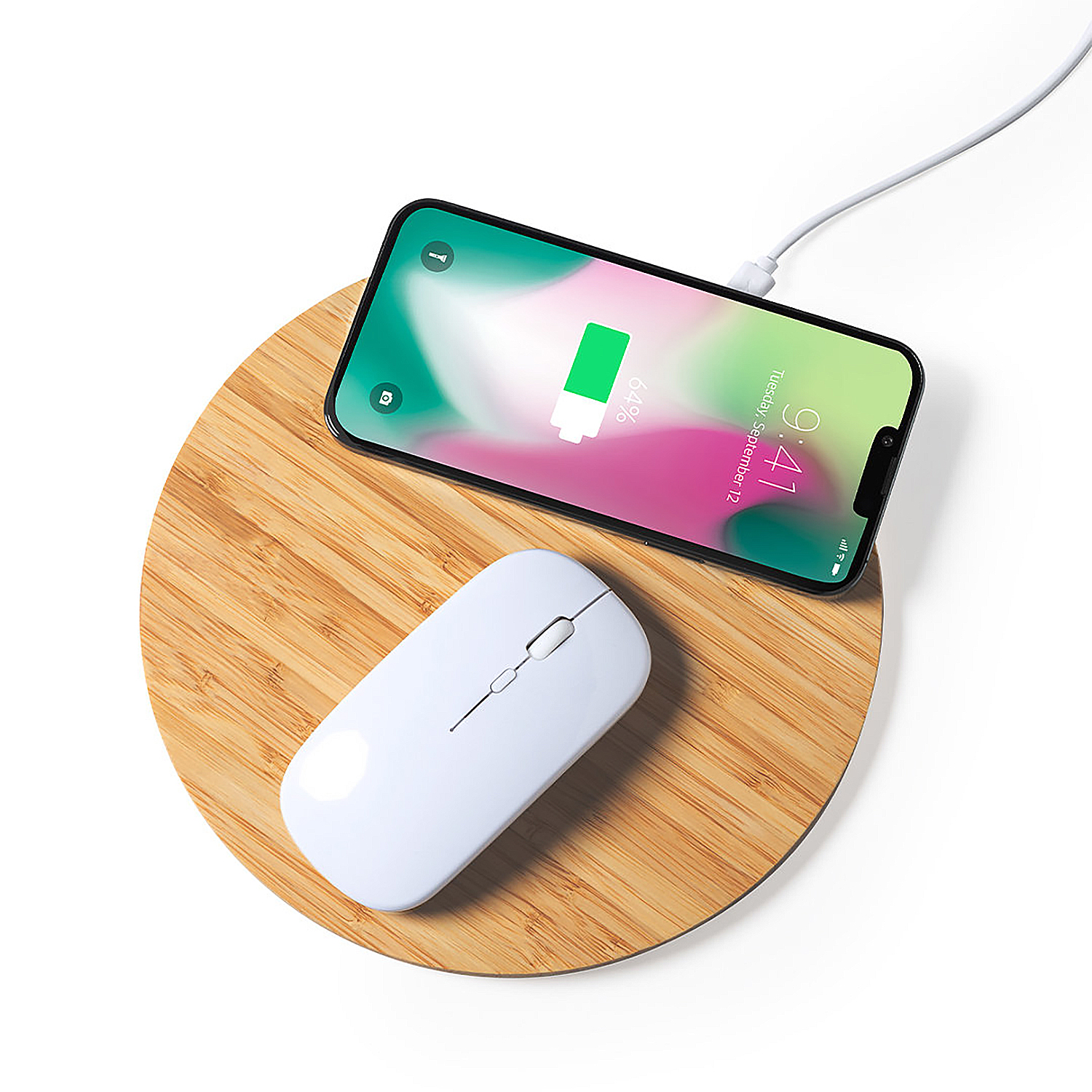Un ratón de computadora blanco y un teléfono inteligente cargando en un posavasos de bambú.