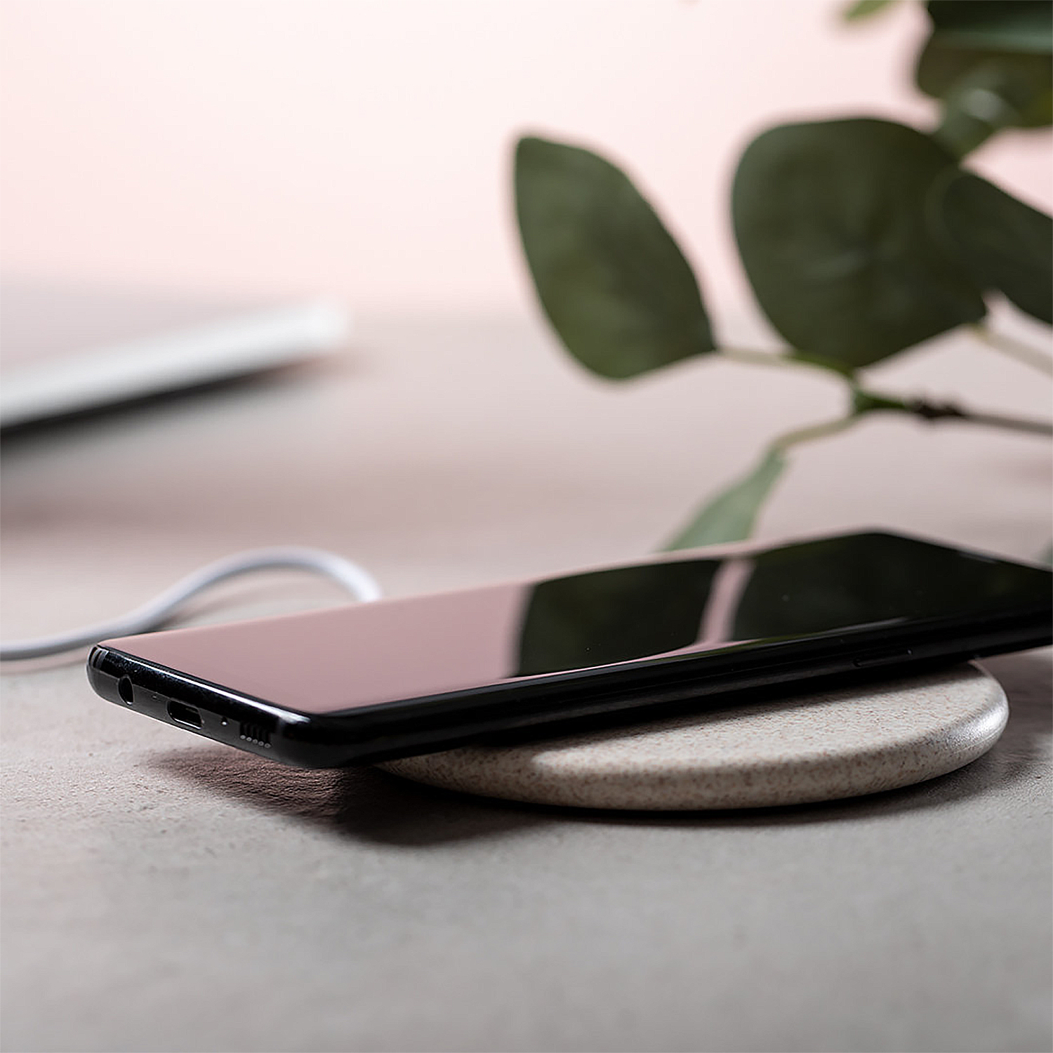 Uno smartphone nero si ricarica su una base di ricarica rotonda e beige.