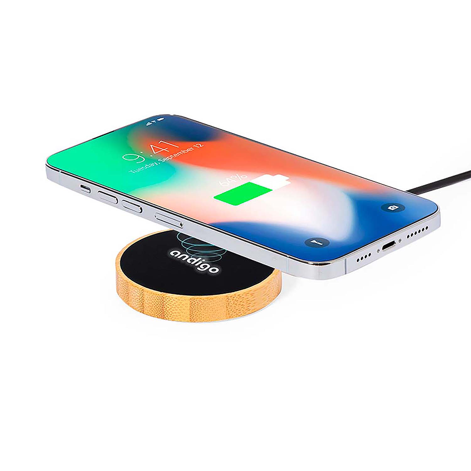 Uno smartphone argentato si ricarica su una base di ricarica rotonda in legno con coperchio nero.