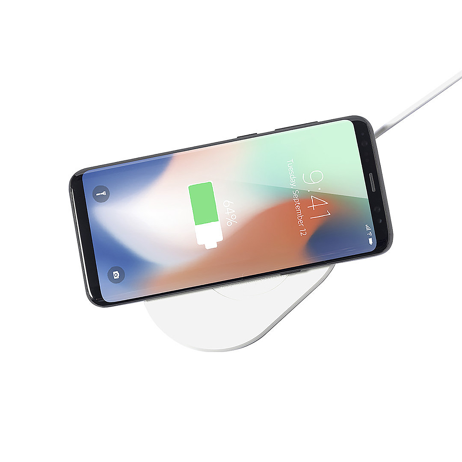 Un smartphone se está cargando en una base de carga inalámbrica blanca.