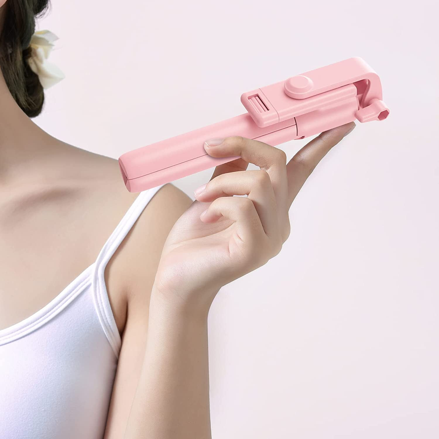 Eine Frau hält einen rosafarbenen Selfie-Stick.