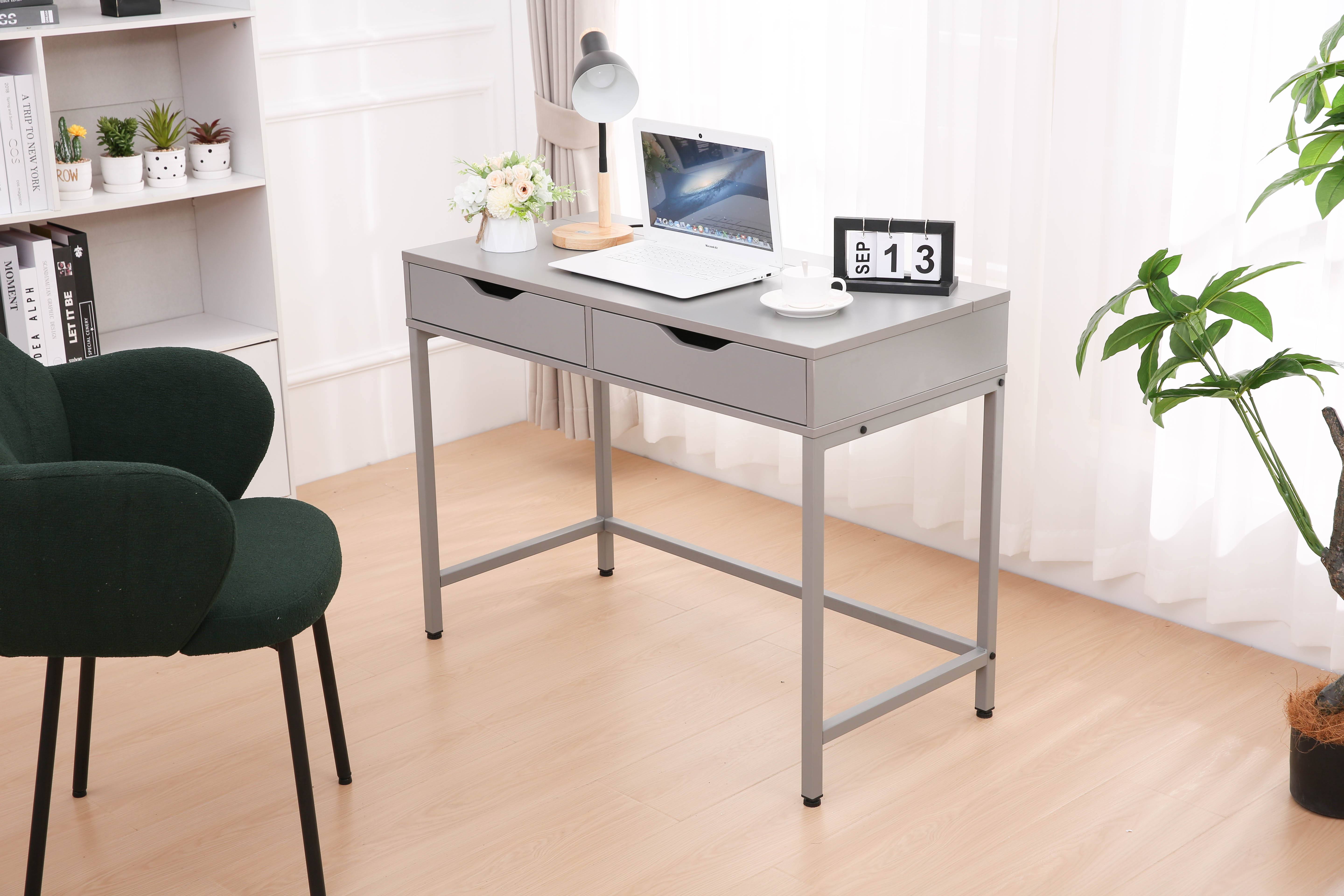 Szare biurko z laptopem, lampą, kwiatami i kalendarzem.