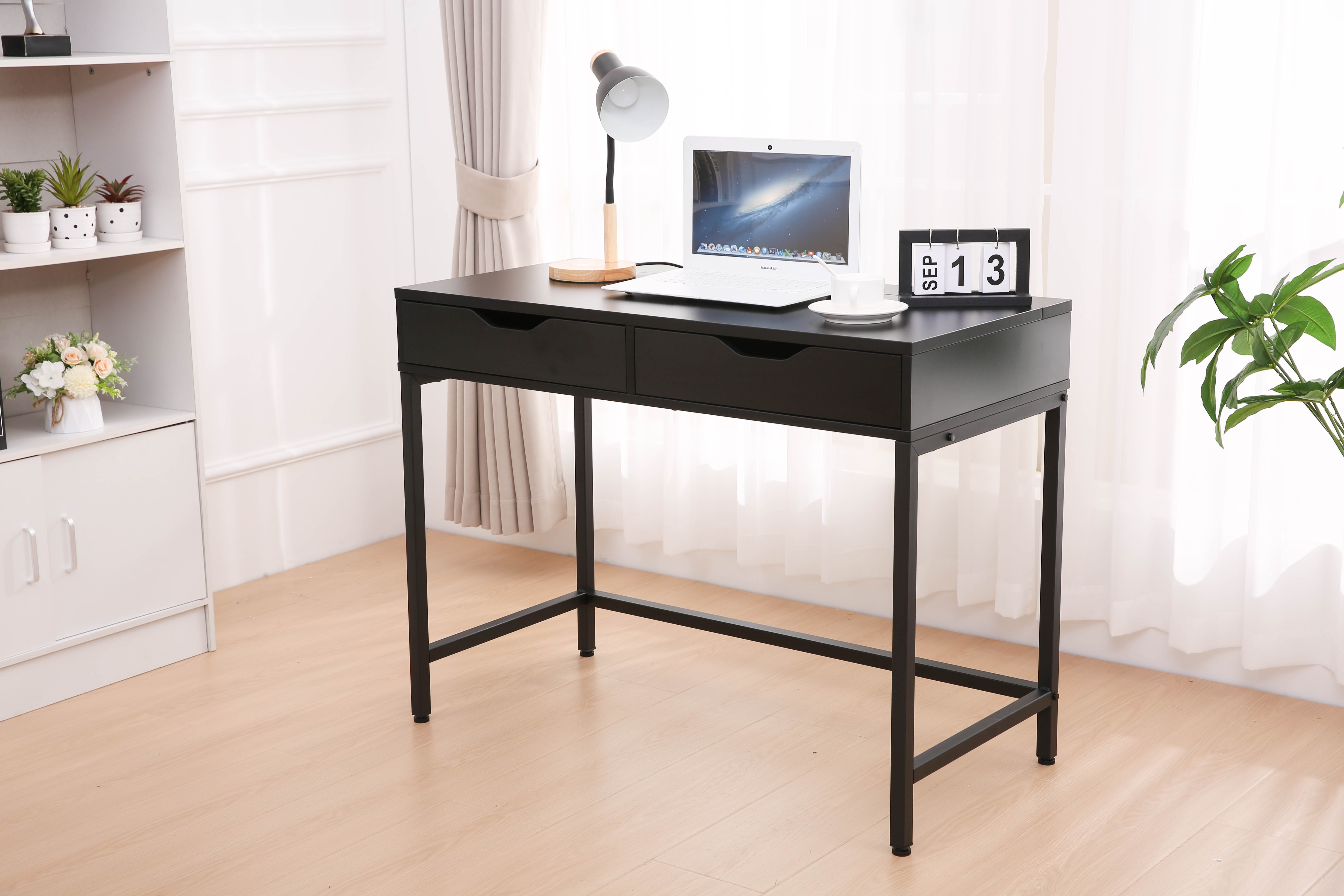 Czarne biurko z laptopem, lampą, kalendarzem i filiżanką.