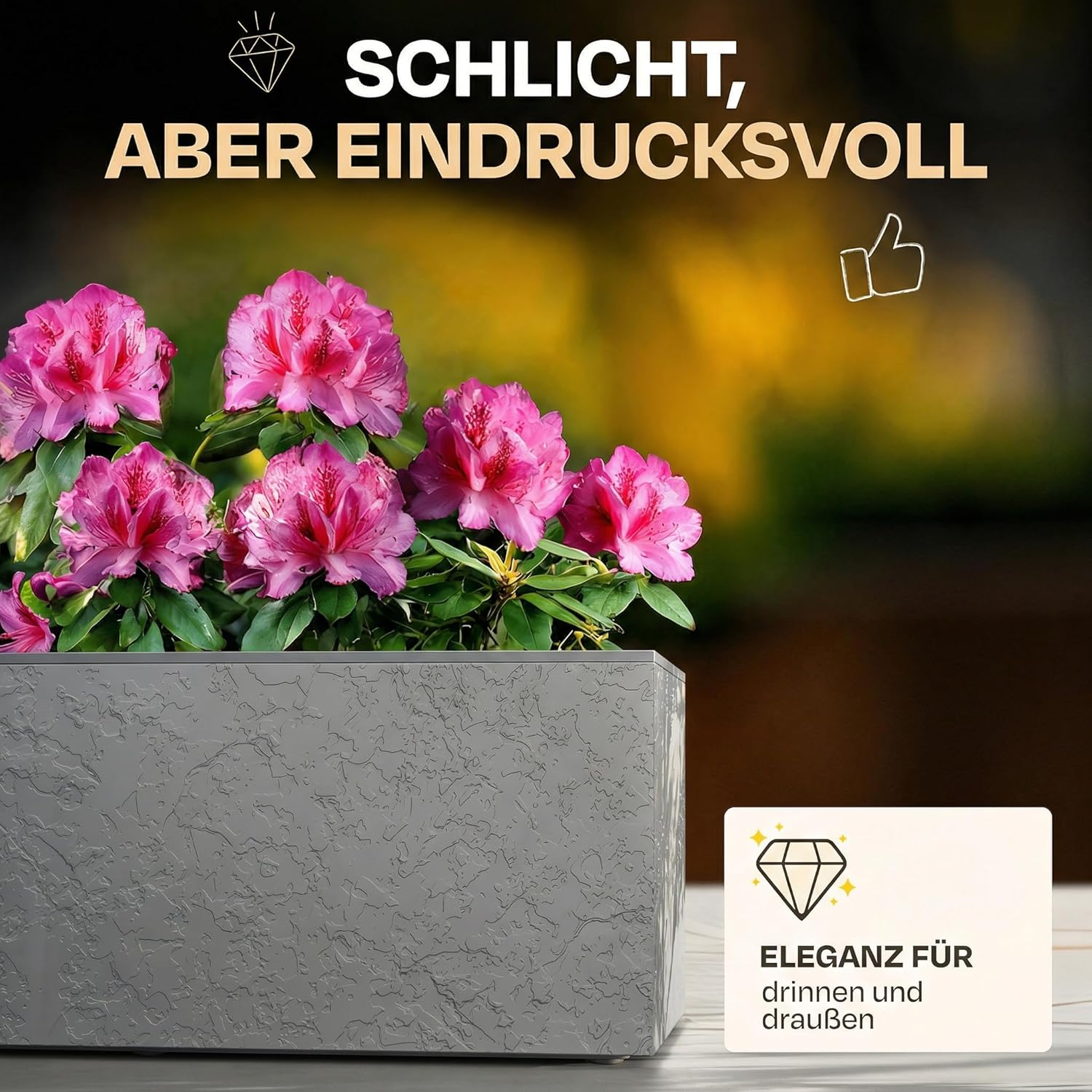 Grauer Pflanzkasten mit pinken Blüten und deutschem Text.