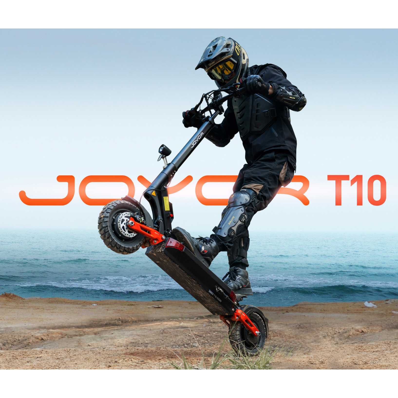 Fahrer auf E-Scooter macht Wheelie am Strand vor dem Meer.