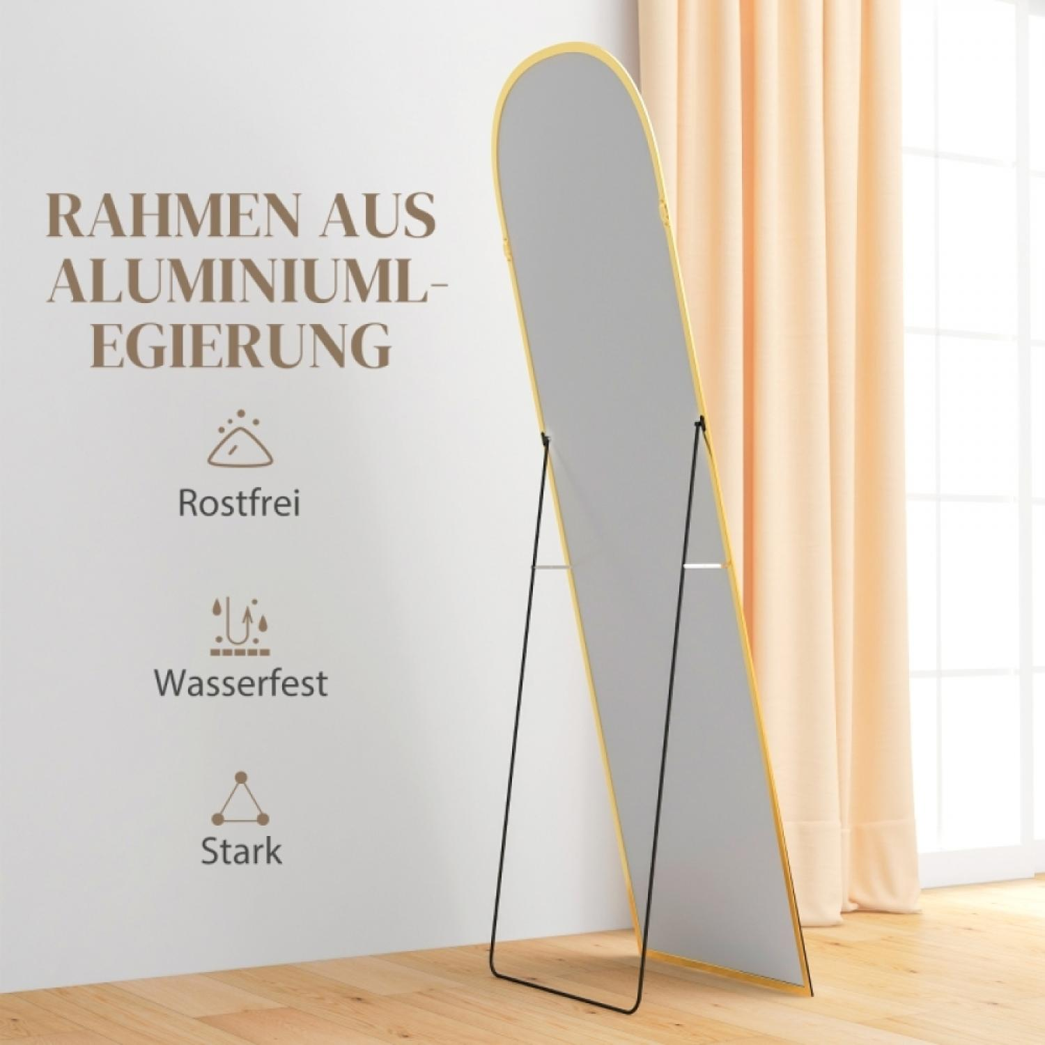 Ein ovaler Standspiegel mit goldenem Rahmen steht auf einem Holzboden.